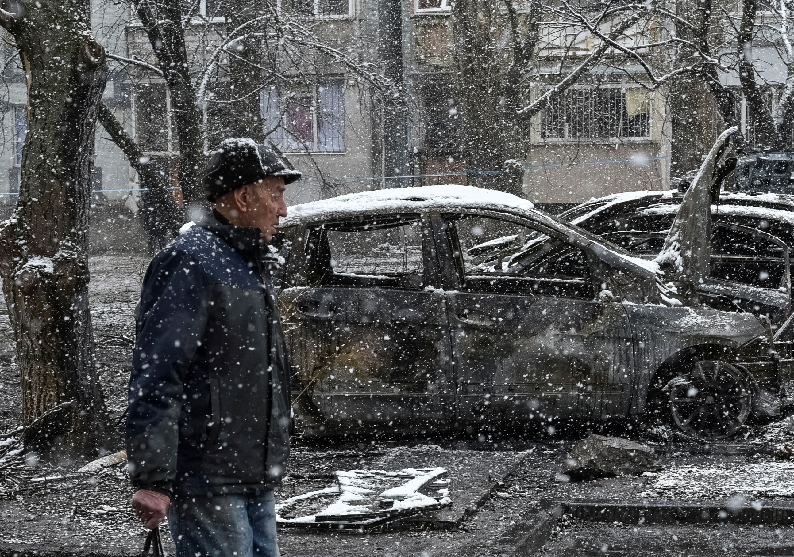 A local passes by burned cars at the site of Russian drone strike, amid Russia's attack on Ukraine, in Dnipro
