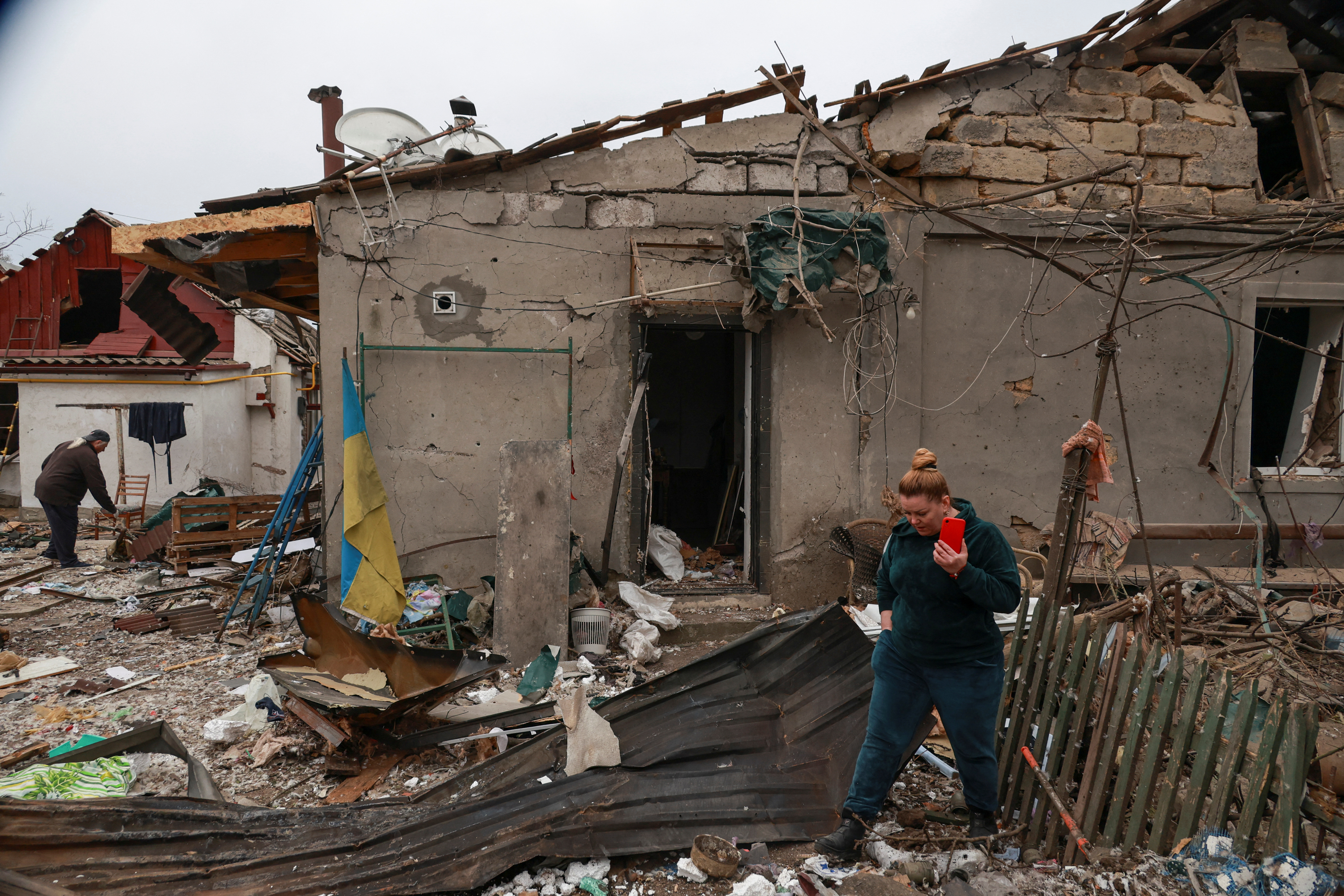 Resident Natalia Steblovska walks in front of her house damaged during a Russian drone attack.