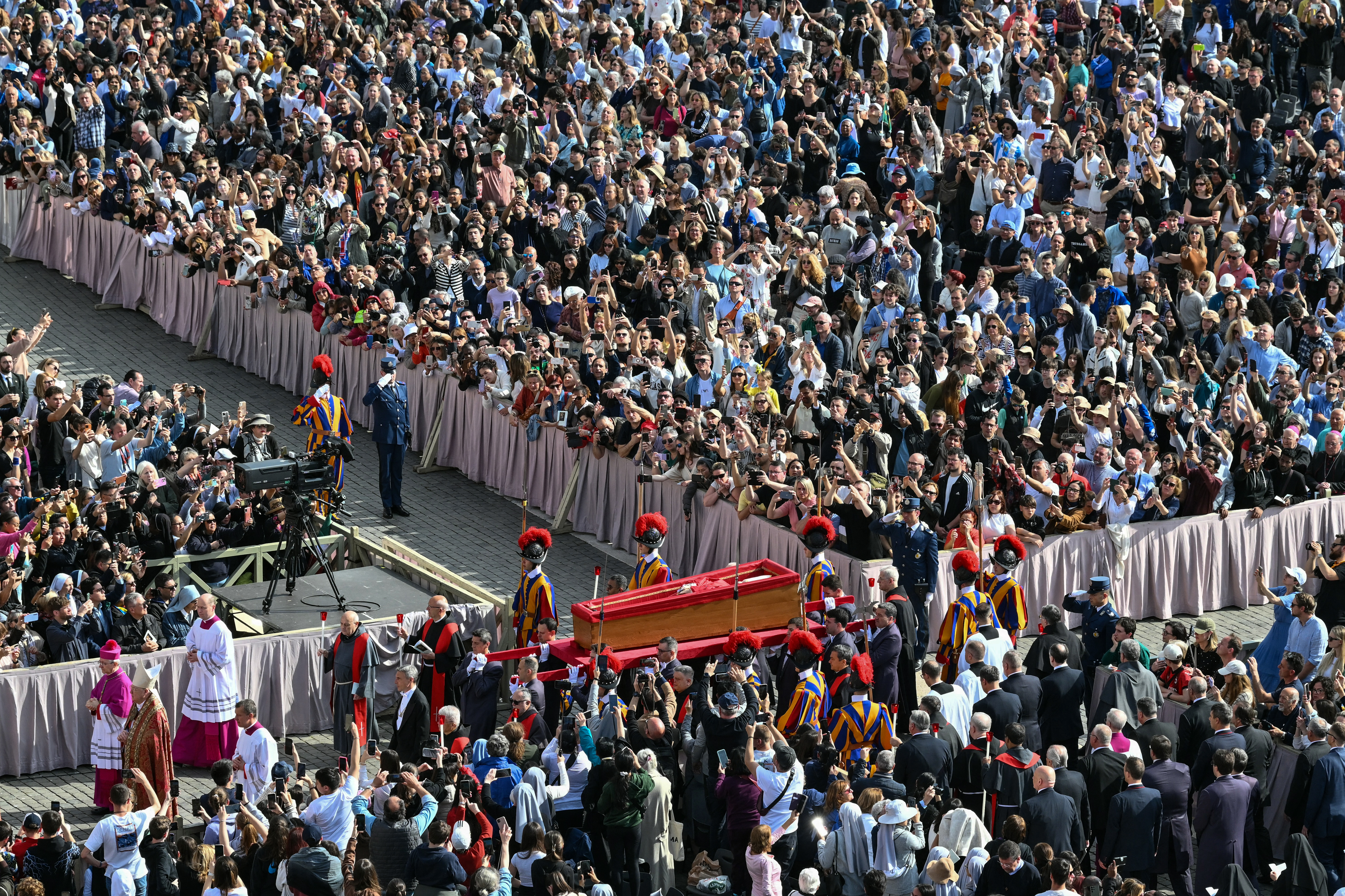 Pallbearers, next to Swiss Guards, carry the coffin of the late Pope Francis as it is transported from the chapel of Santa Marta to St Peter's Basilica, following the Pope's death, in the Vatican on April 23, 2025. The Pope died of a stroke, the Vatican announced hours after the death on April 21, 2025, of the 88-year-old reformer who inspired devotion but riled traditionalists during 12 years leading the Catholic Church. (Photo by Alberto PIZZOLI / AFP)
