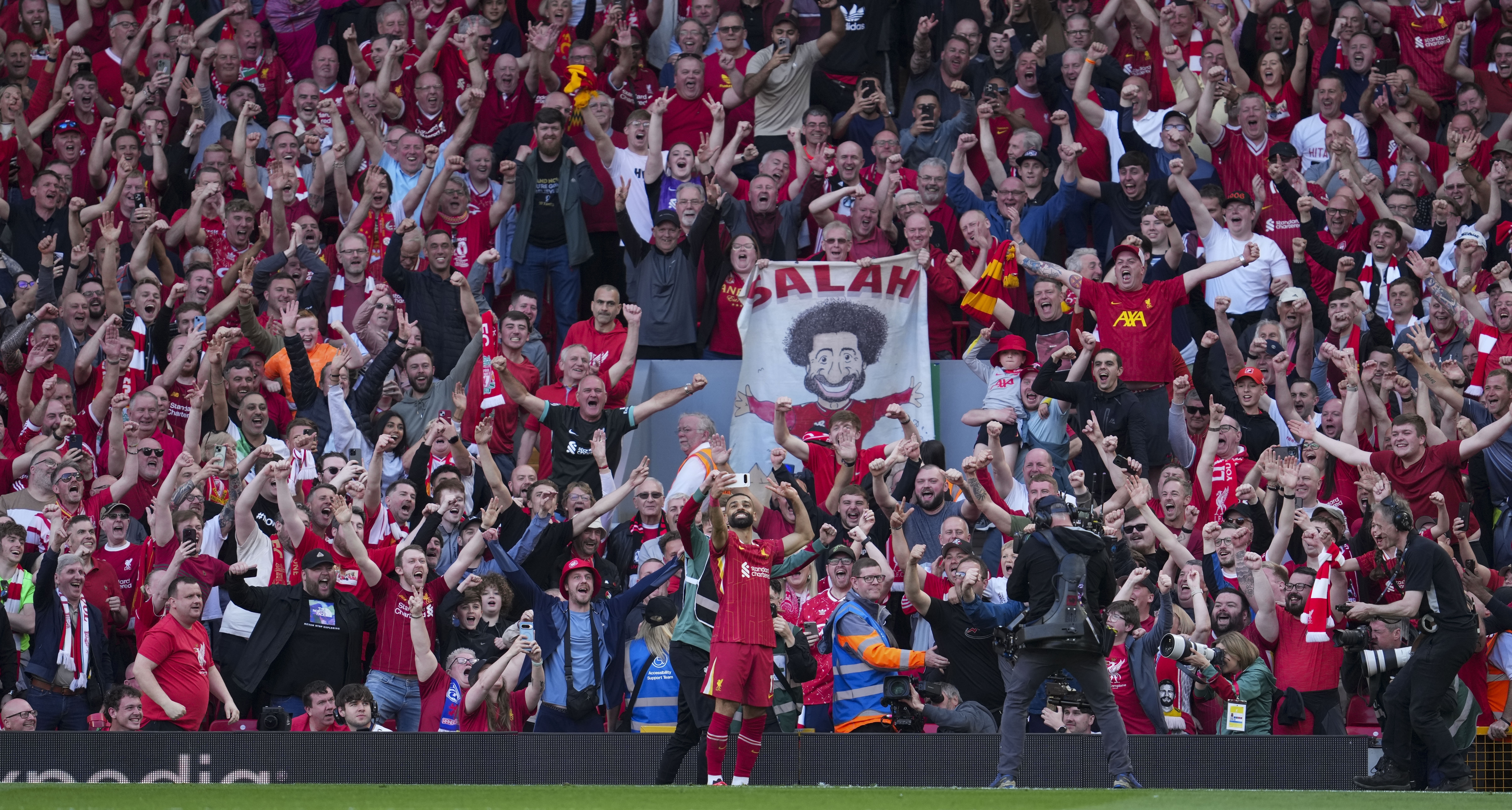 Liverpool's Mohamed Salah takes a selfie with a fans smartphone as he celebrates after scoring his side's fourth goal during the English Premier League soccer match between Liverpool and Tottenham Hotspur at Anfield in Liverpool, England, Sunday, April 27, 2025. (AP Photo/Jon Super)