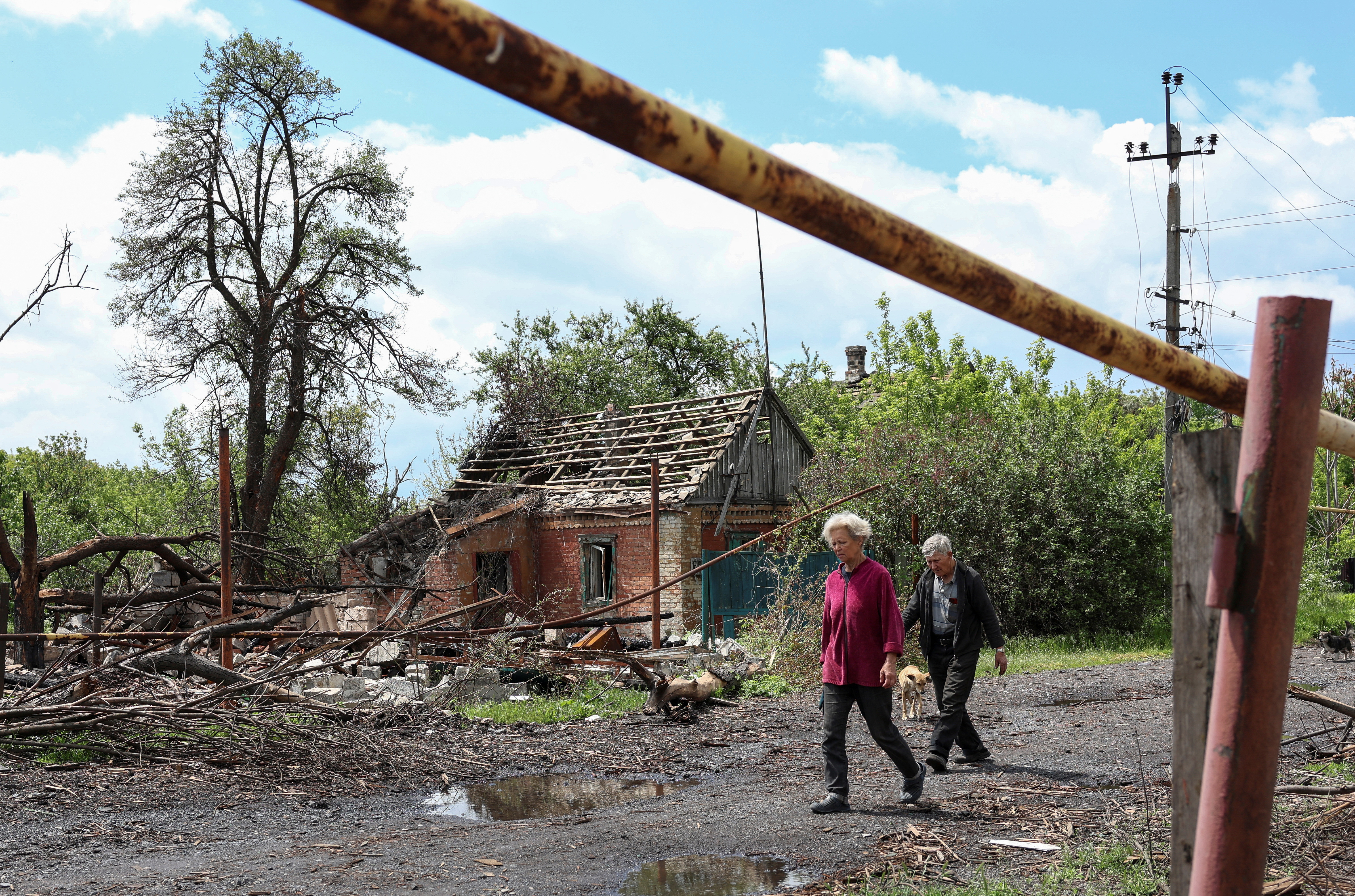 Residents walk at a street near a building damaged by Russian military strikes, amid Russia's attack on Ukraine, in the frontline town of Pokrovsk, Donetsk region, Ukraine May 21, 2025. REUTERS/Anatolii Stepanov