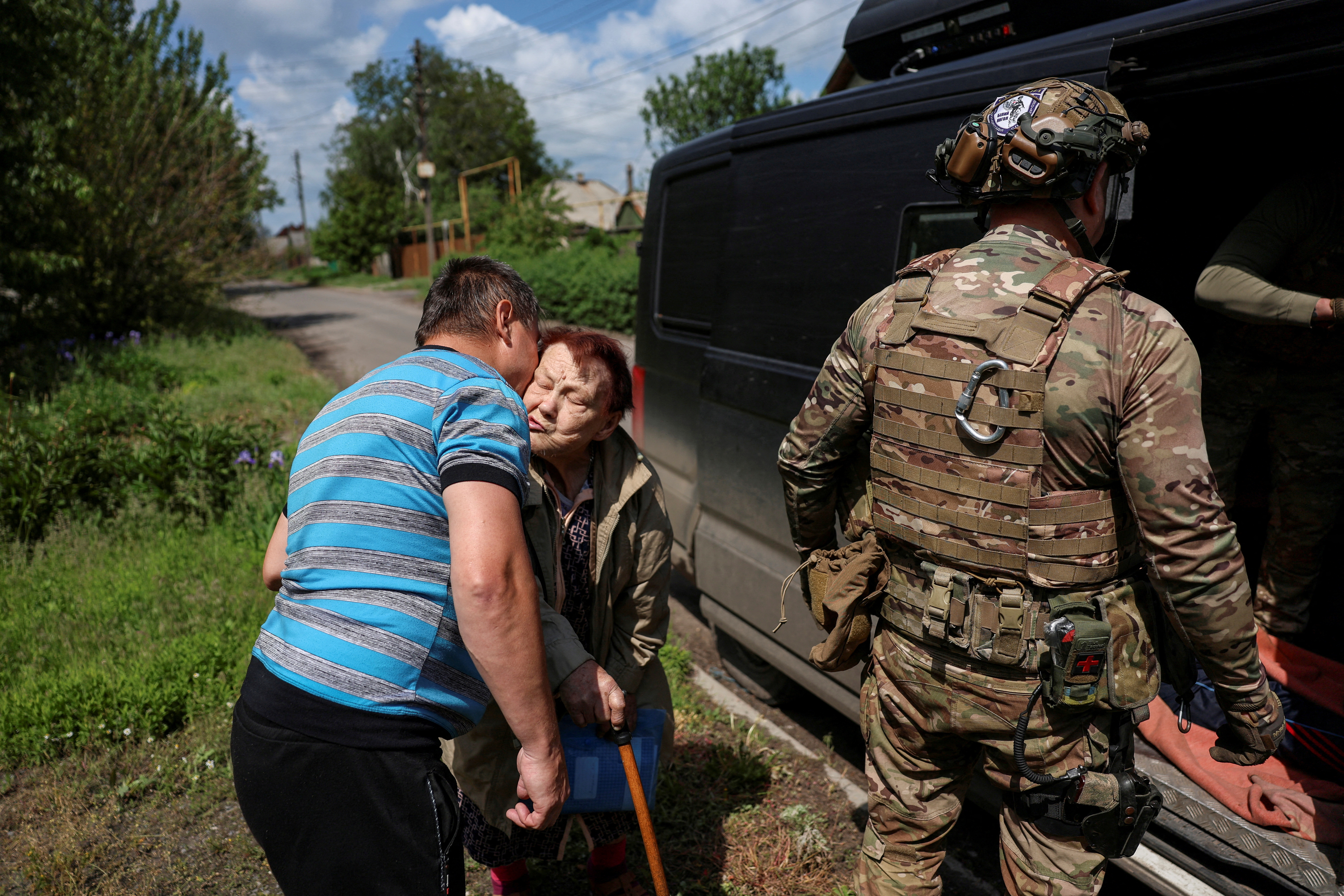 A son says goodbye and kisses his mother as police officers evacuate people from front-line towns.