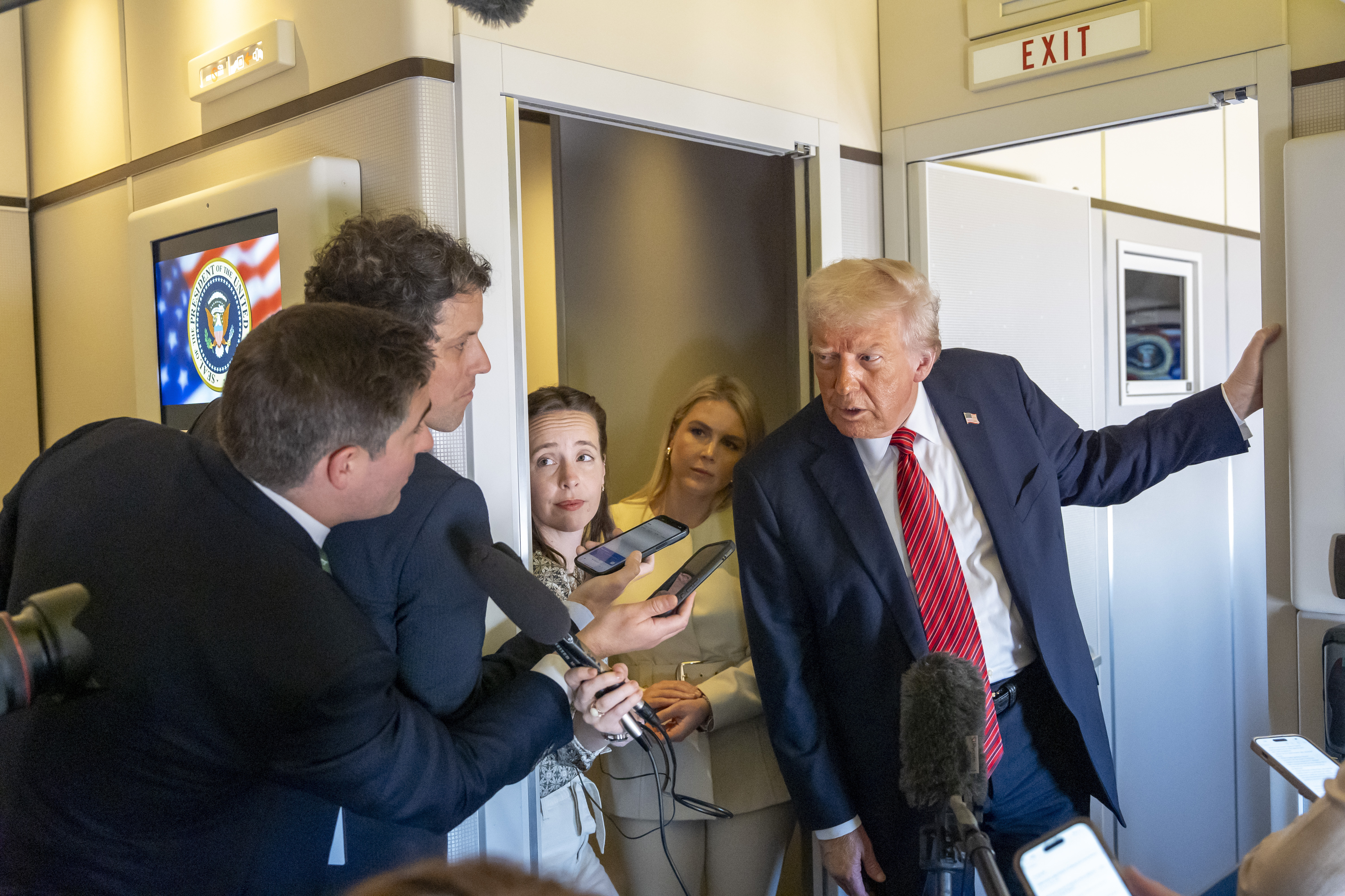 Donald Trump leans over to talk to the press in Air Force One.