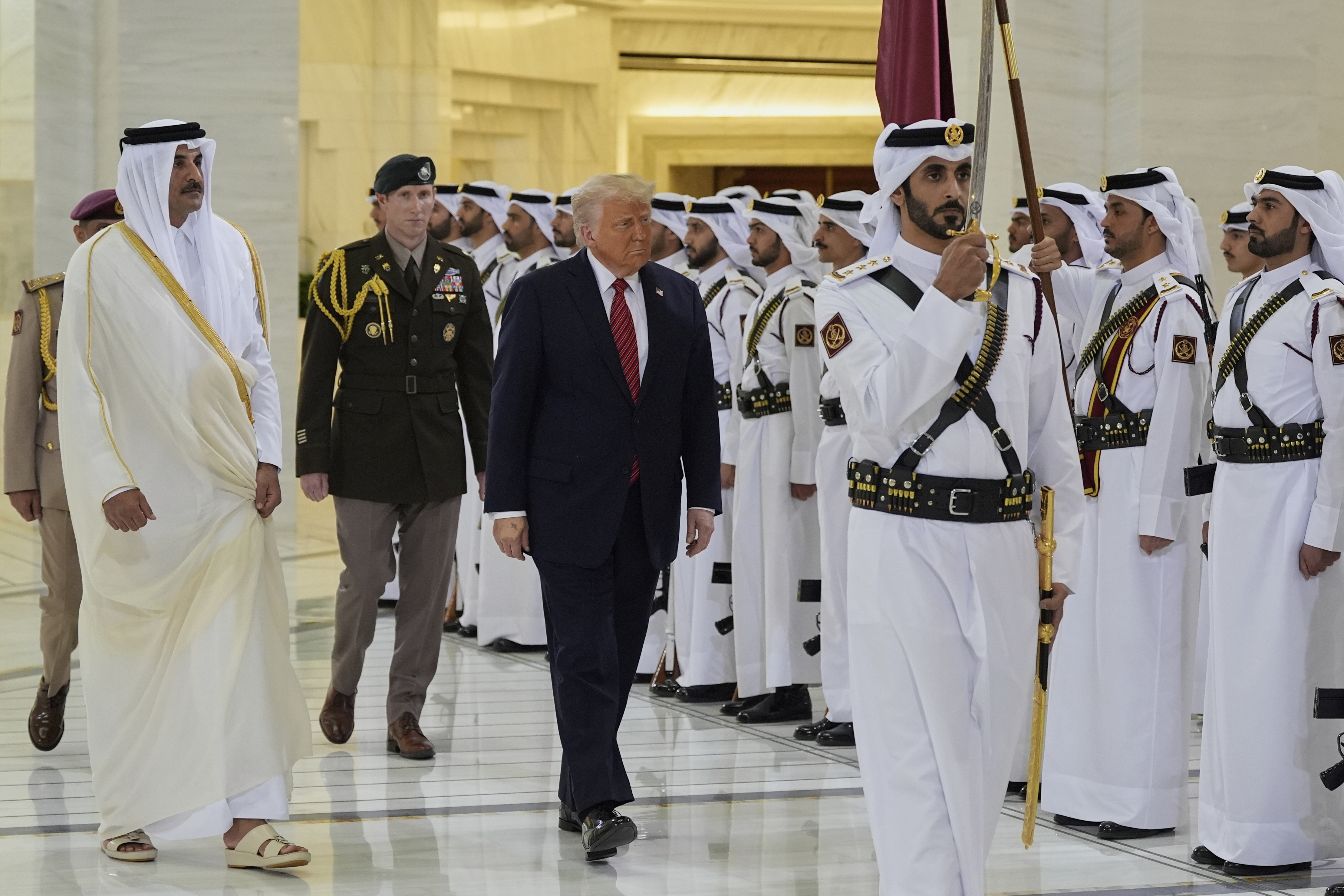 Trump walks with Emir Sheikh Tamim bin Hamad Al Thani as guard with a sword leads the way.