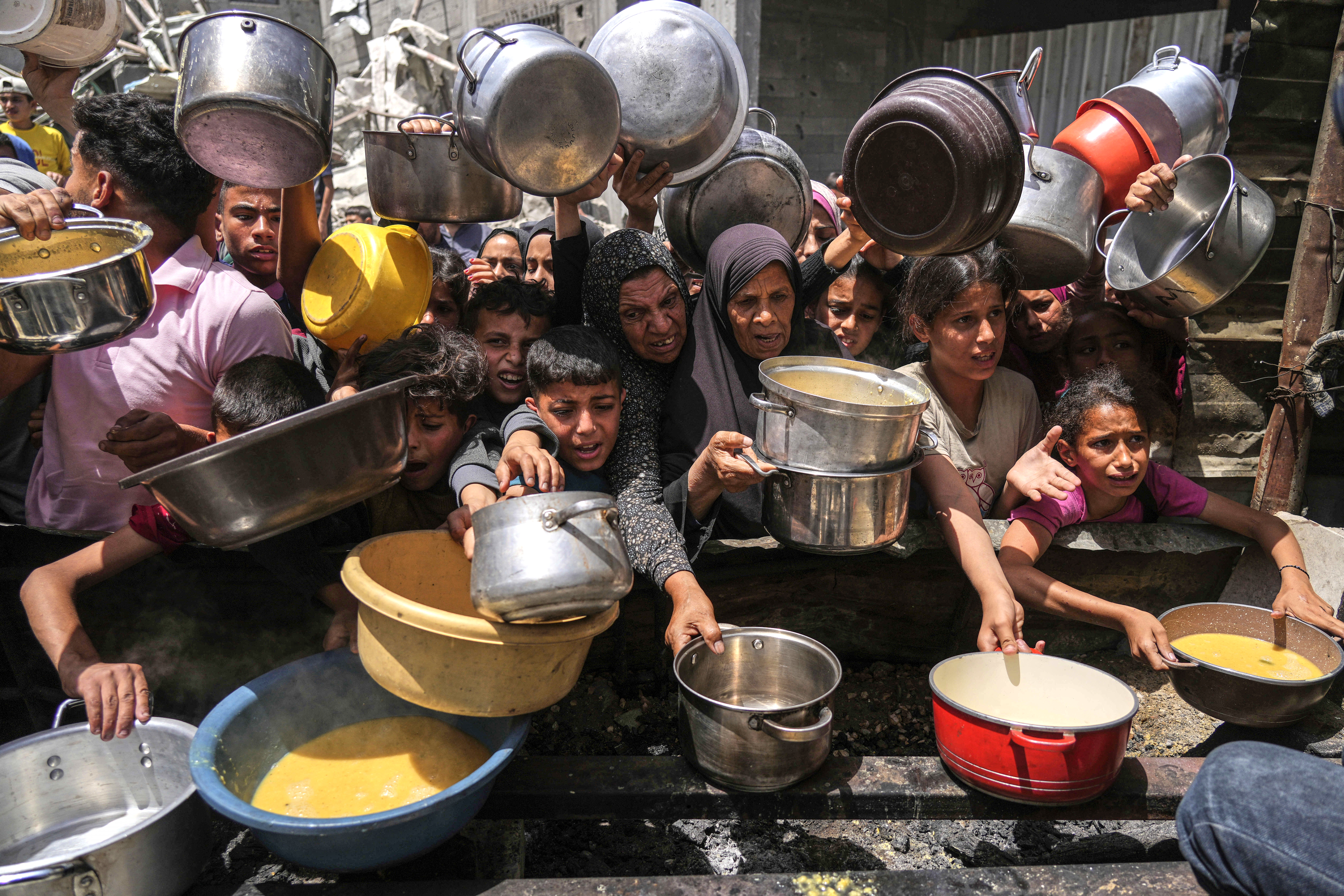Palestinians struggle to get donated food at a community kitchen in Jabalia, northern Gaza Strip,