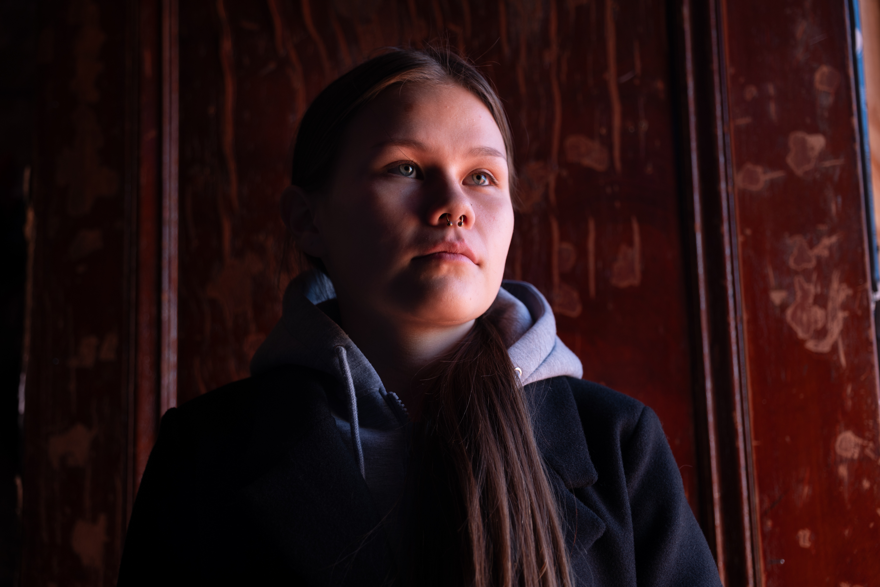 A portrait photo shows Elle Harris standing in front of a brown wooden door