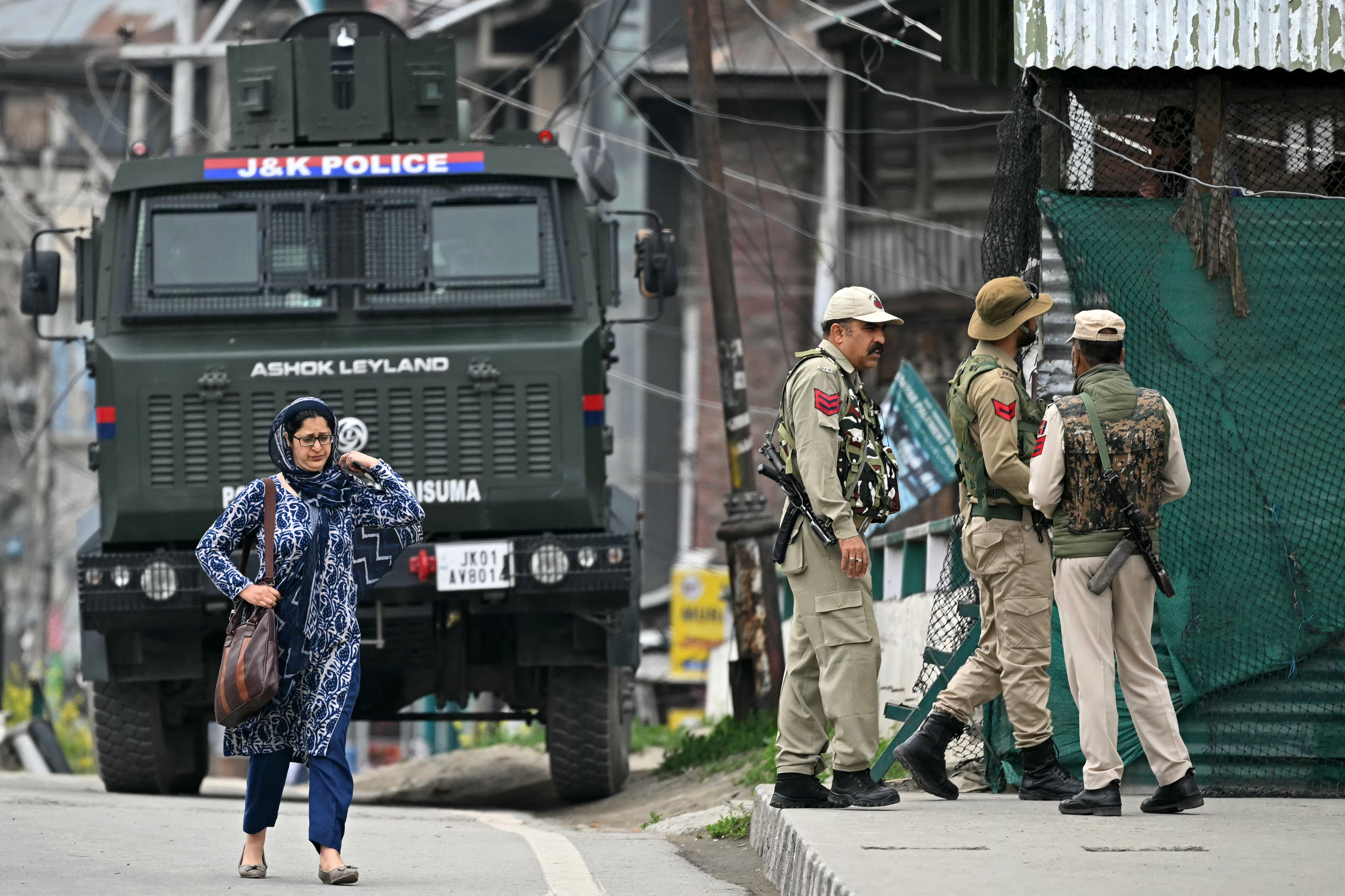 Indian policemen stand guard as a woman walks along a street in Srinagar on May 9, 2025.