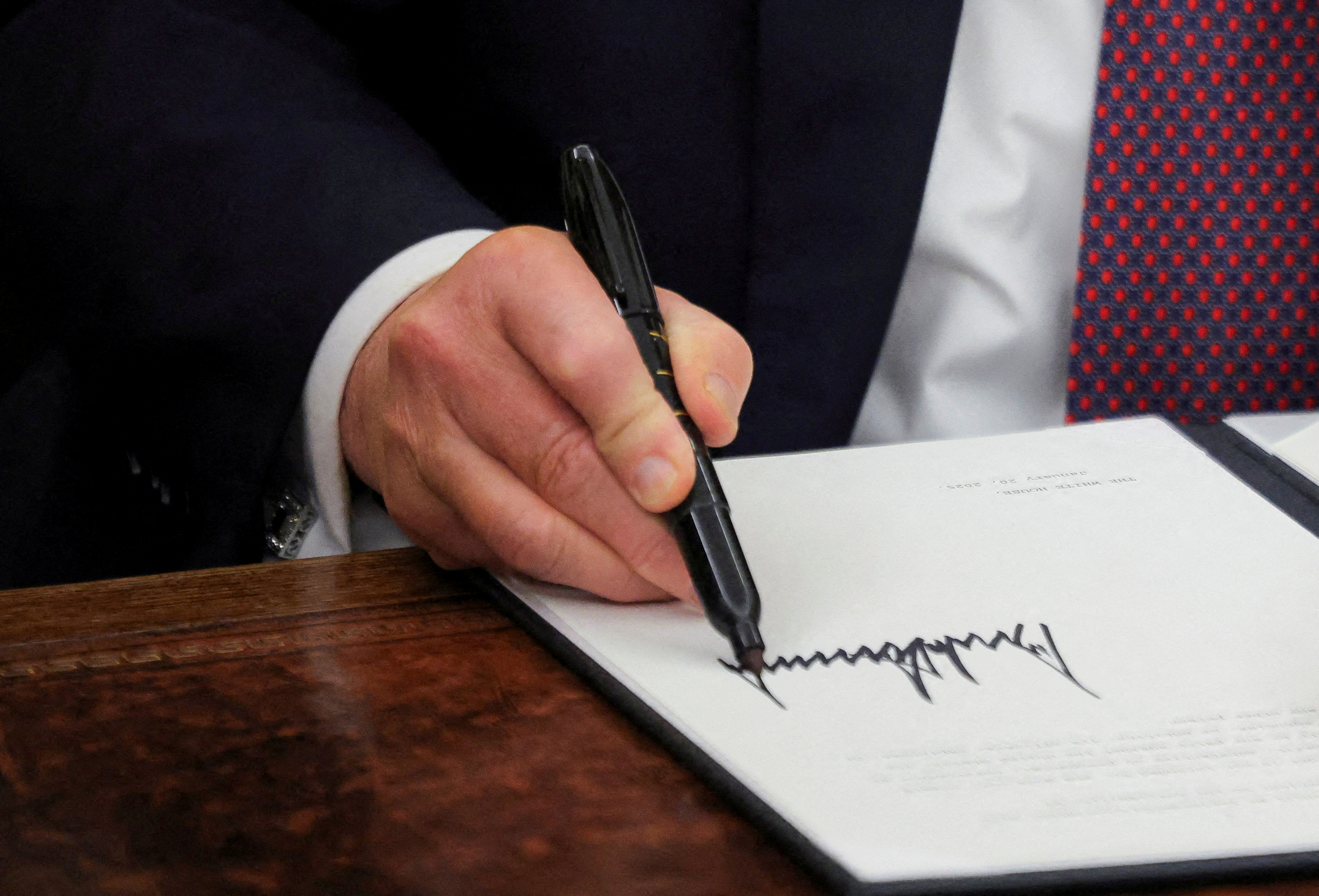 FILE PHOTO: U.S. President Donald Trump signs documents as he issues executive orders and pardons for January 6 defendants in the Oval Office at the White House on Inauguration Day in Washington, U.S., January 20, 2025. REUTERS/Carlos Barria/File Photo