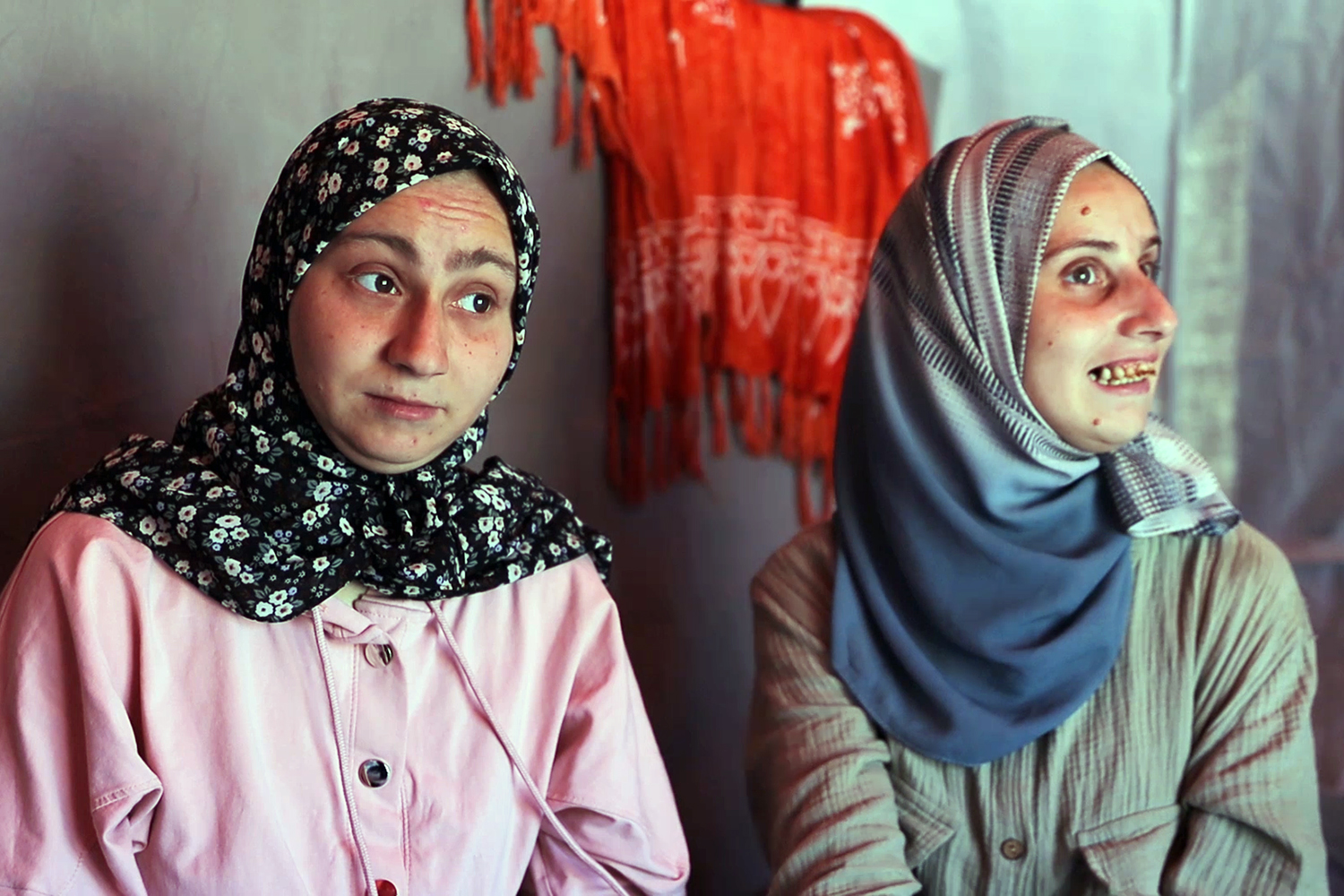 Aseel and Afaf al-Eish sit inside their family’s tent in northern Gaza. Living with disabilities and celiac disease, the sisters endure displacement in a world that often overlooks their pain. [Noor Al-Halabi/Al Jazeera]