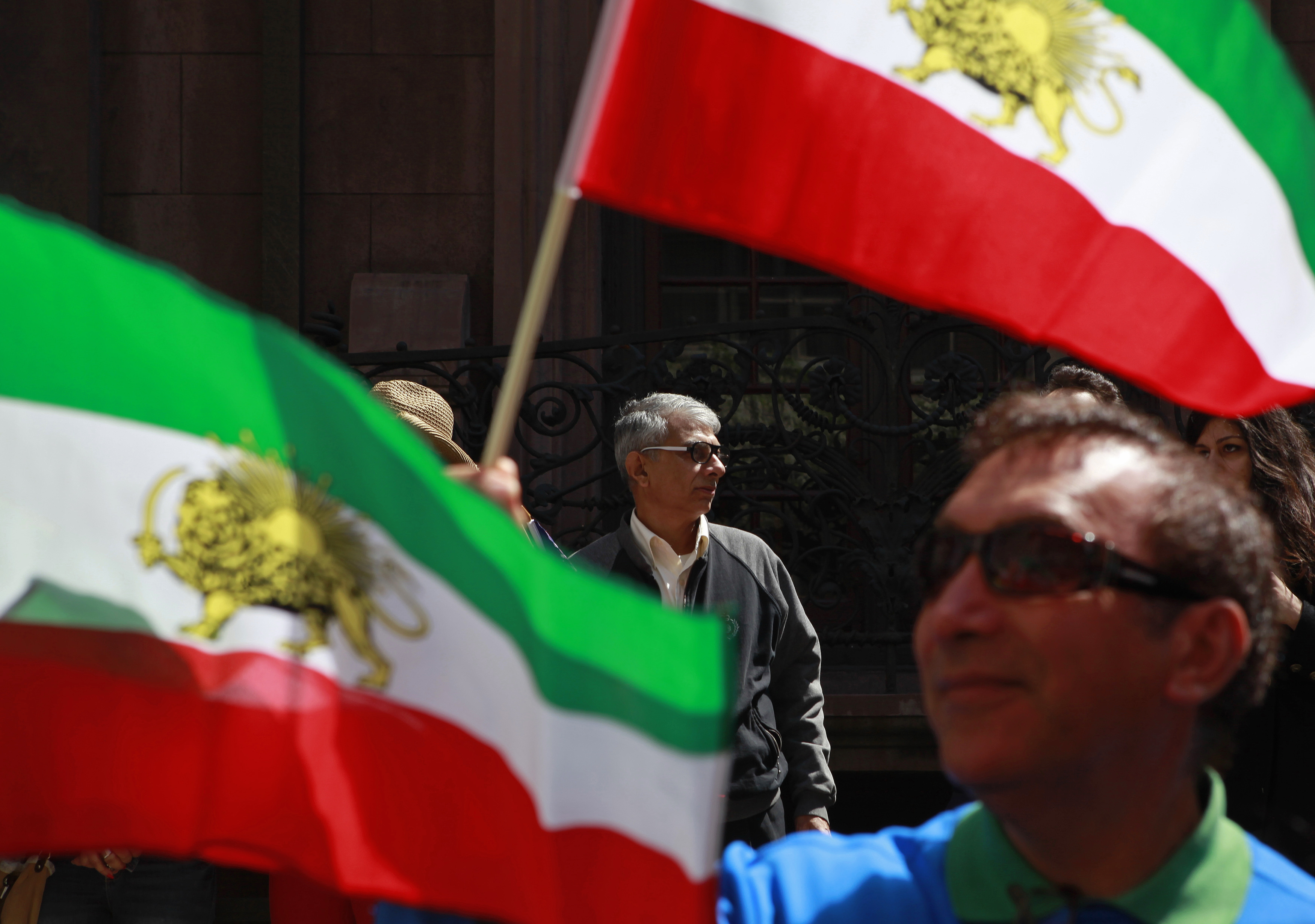 People watch the 10th Annual Persian Day Parade behind Iranian state flags used before the revolution, in New York, April 14, 2013. REUTERS/Carlo Allegri (UNITED STATES - Tags: SOCIETY)