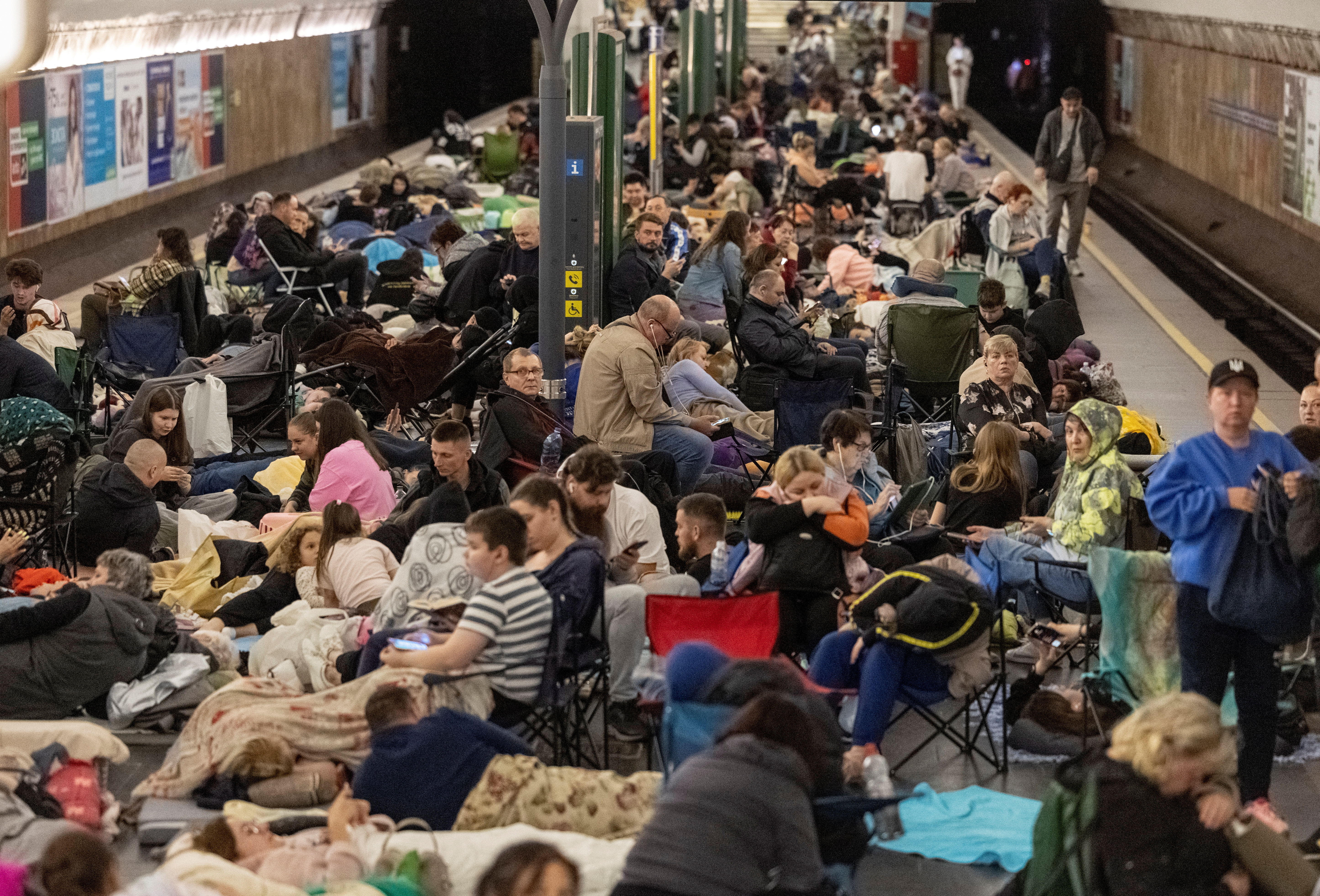 people sit on the ground in an underground train station