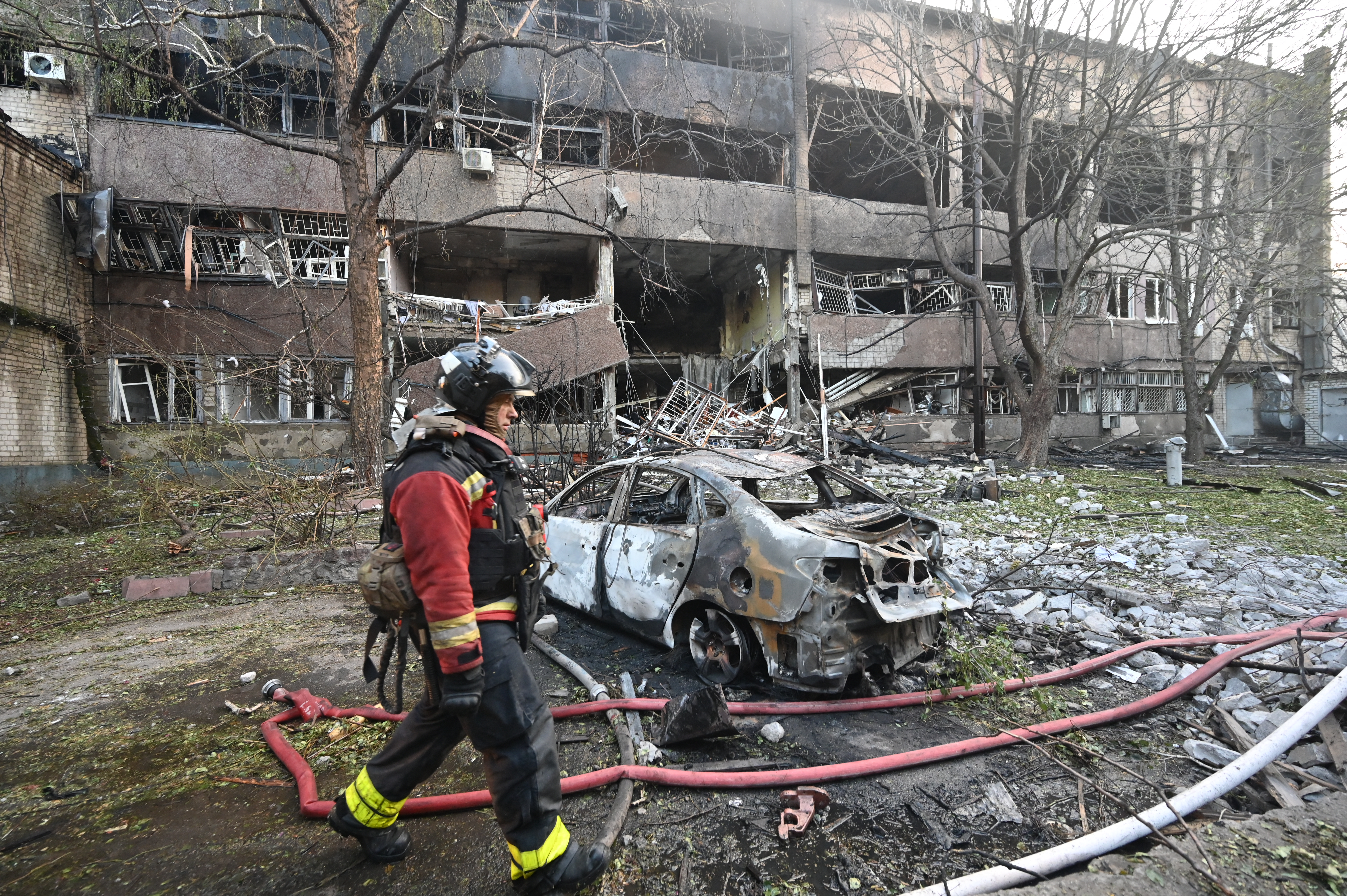 A firefighter walks past a burnt car following a Russian drone strike in Kharkiv, Ukraine