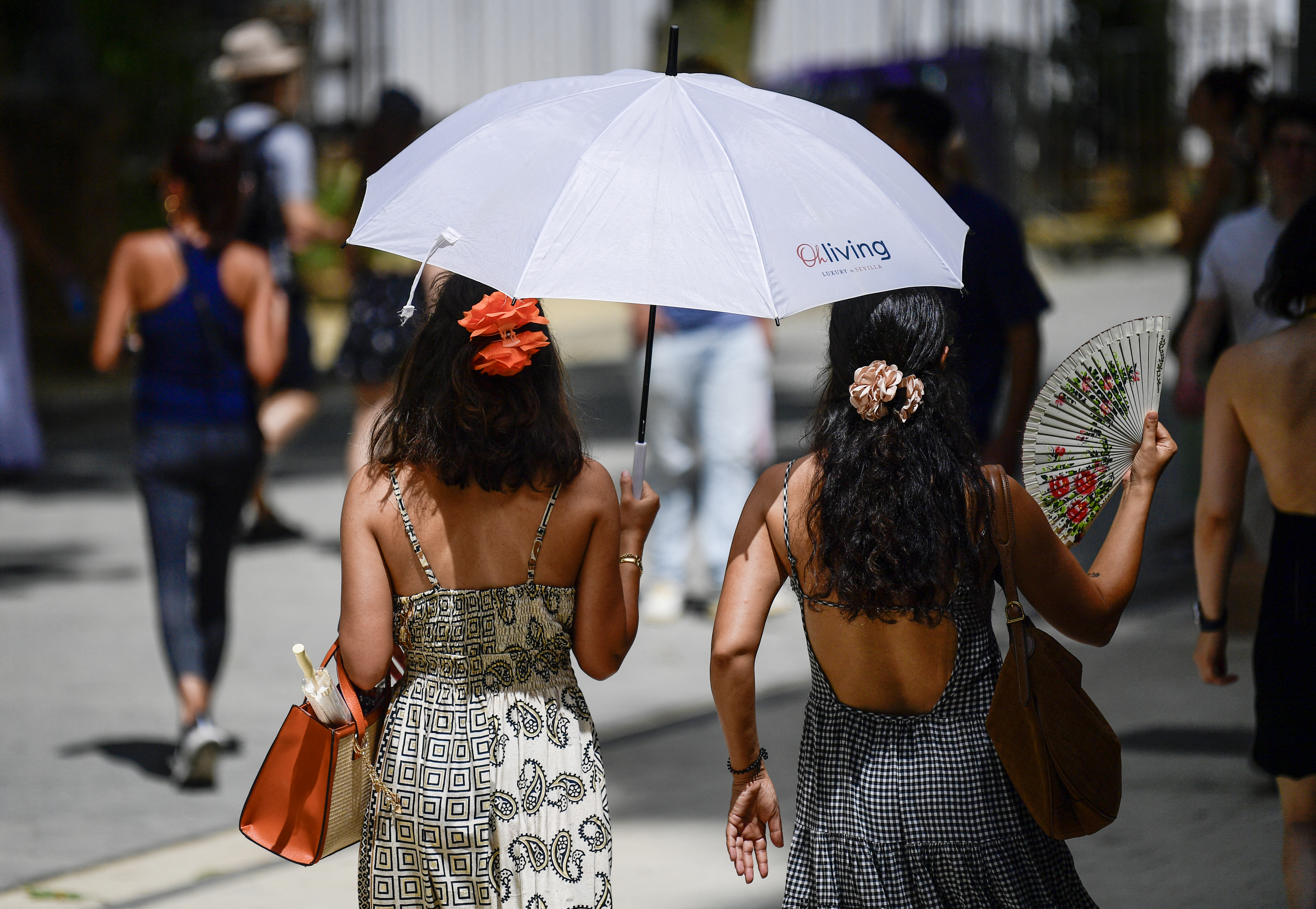 Women use umbrellas and fans to stay cool during the first heatwave of the summer in Seville, Spain on June 28, 2025.