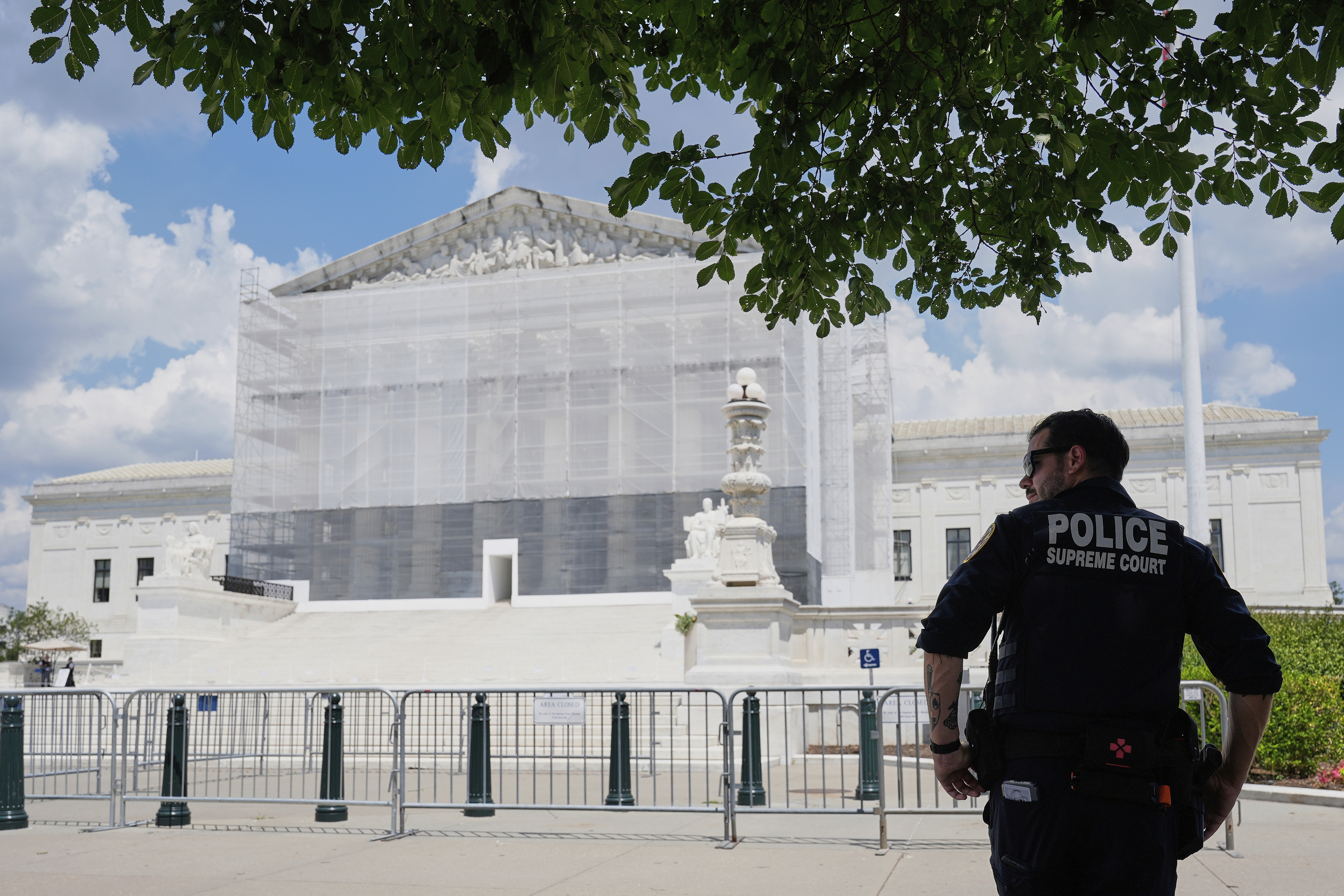 The US Supreme Court, seen in June 2025, with scaffolding. A law enforcement officer stands outside.