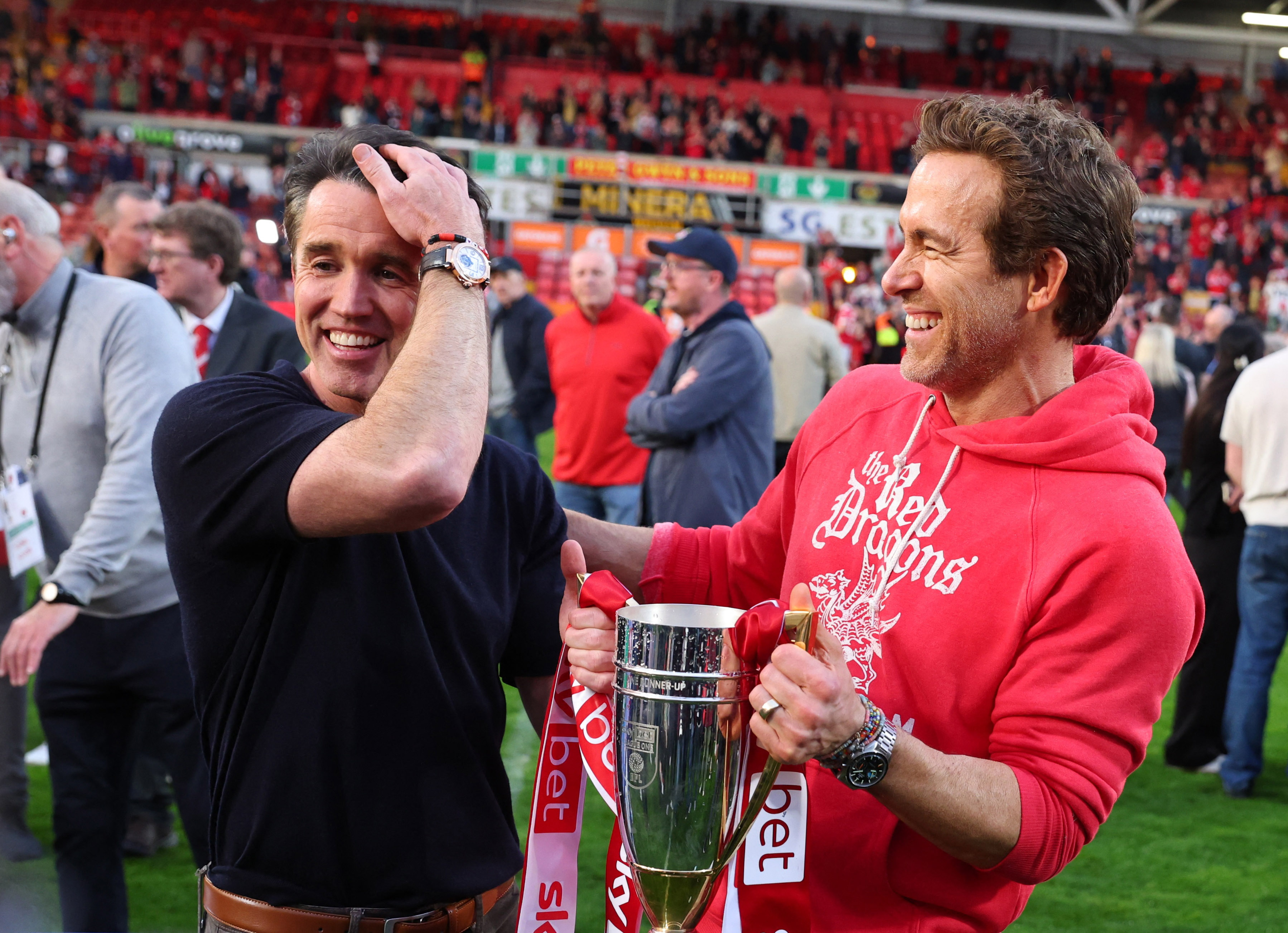 Actors and Wrexham owners Rob McElhenney and Ryan Reynolds celebrate with a trophy after being promoted to the Championship 