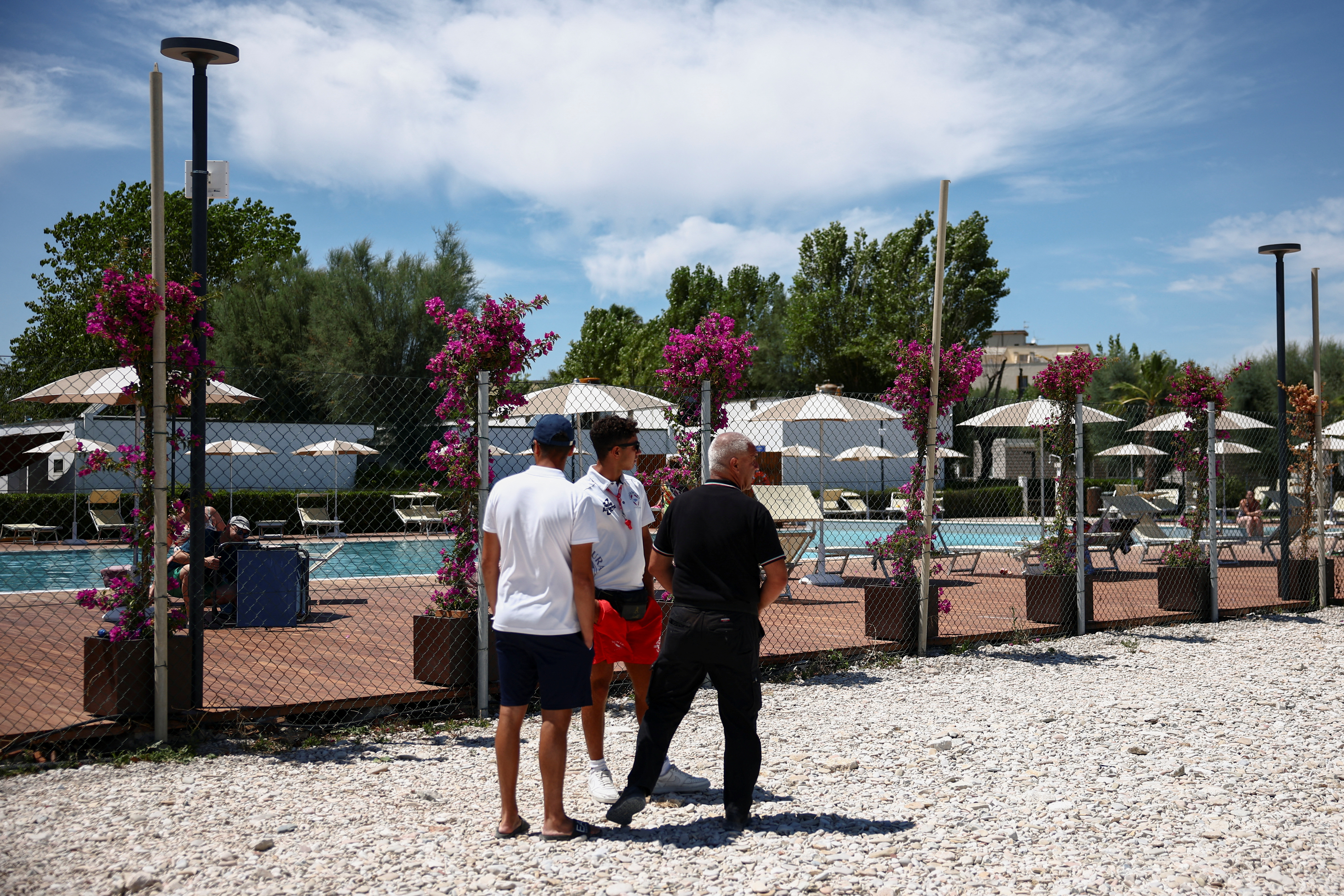 Workers stand near the swimming pool of the 'Le Mimose' resort, where skydiver Felix Baumgartner's paraglider crashed, killing him and injuring a hotel employee on the ground, in Porto Sant'Elpidio, Italy