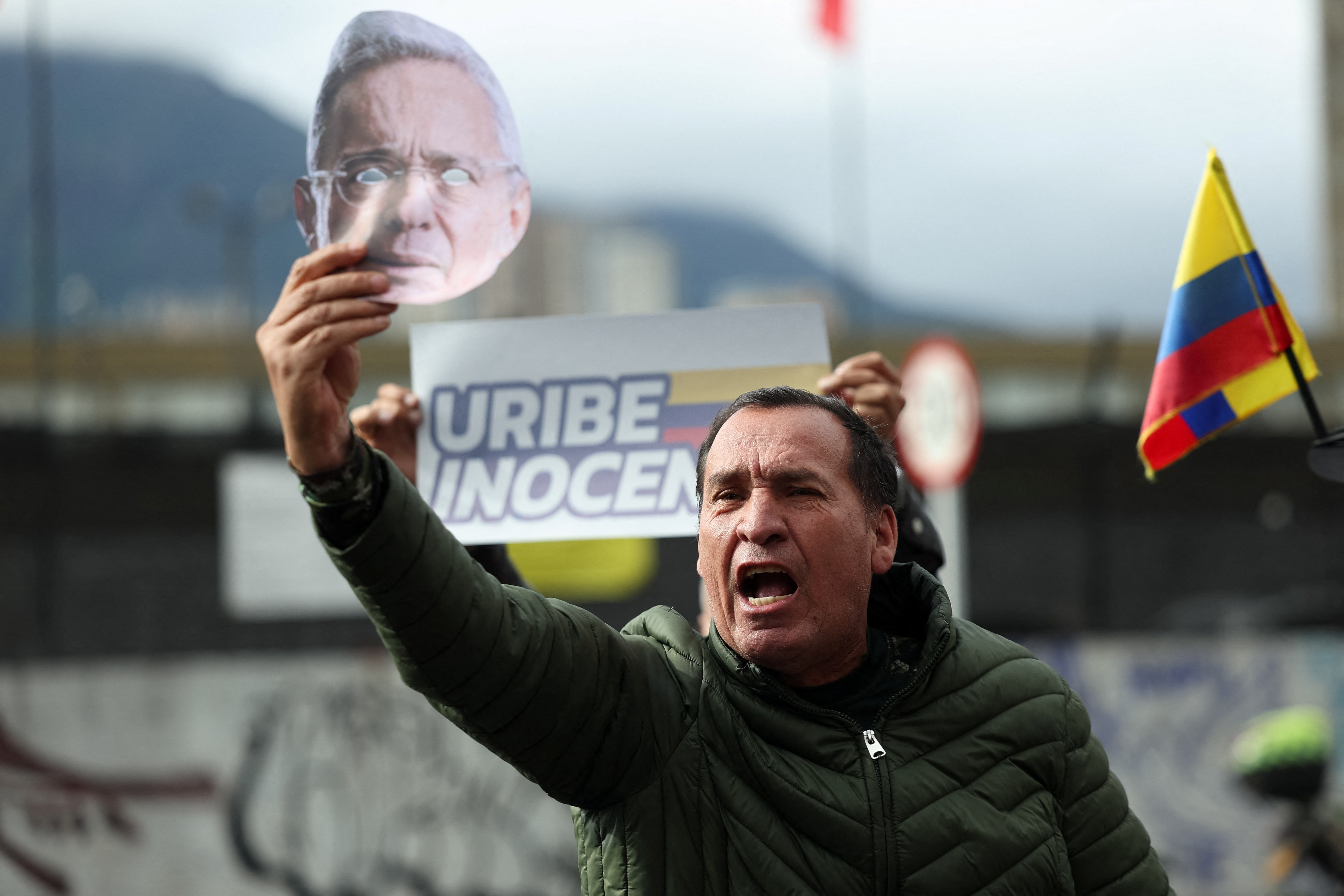 A man holds a mask depicting former Colombian President Alvaro Uribe, during a protest in support of Uribe outside the Paloquemao court complex ahead of the ruling in a criminal case against him, in Bogota, Colombia, July 28, 2025. REUTERS/Luisa Gonzale