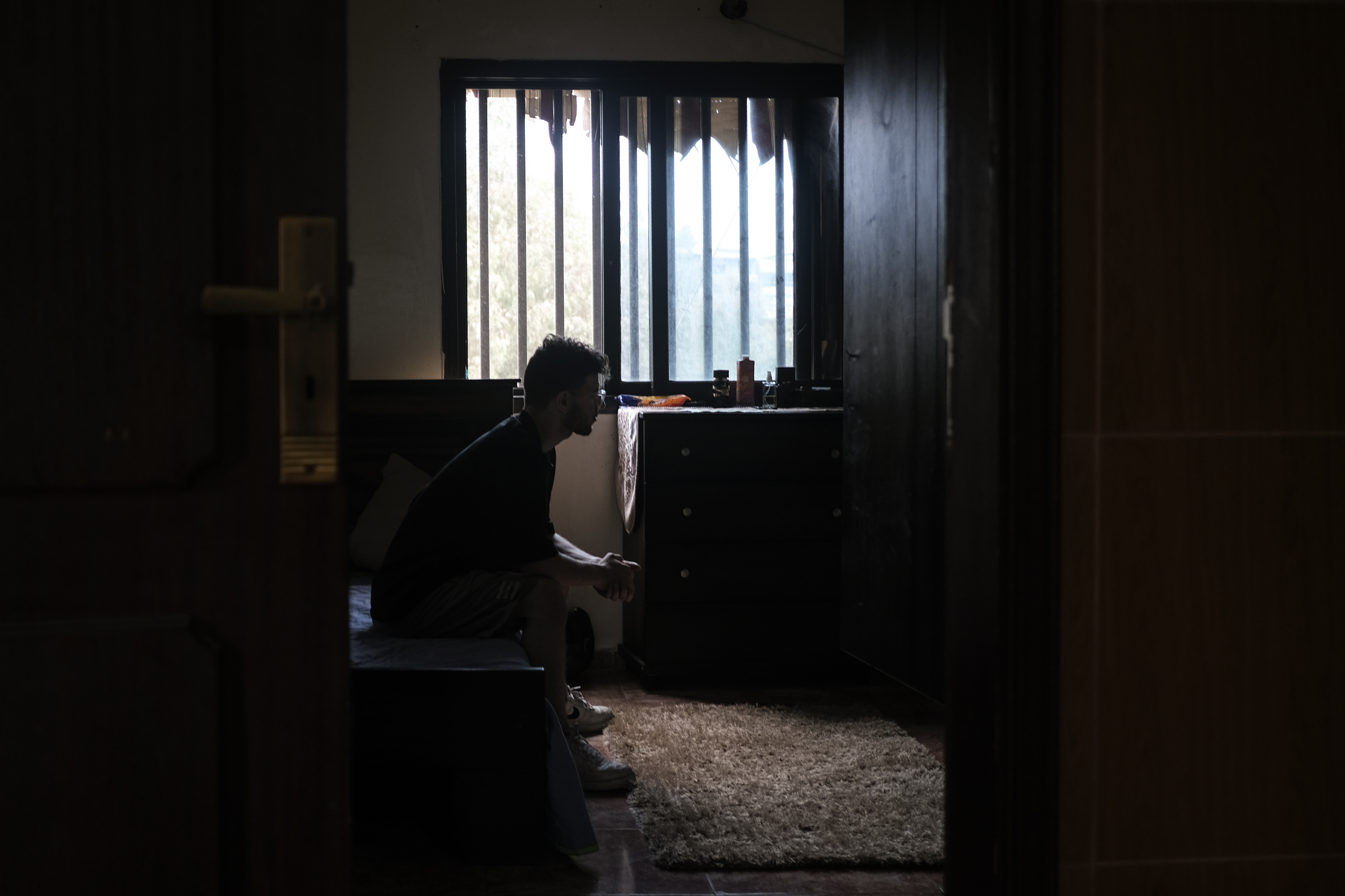 Hussein Fneish sits on his bed in his new house in Laylake after being displaced from his destroyed home in Hay El Selom following an airstrike by Israel during the war in 2024. [João Sousa/Al Jazeera]