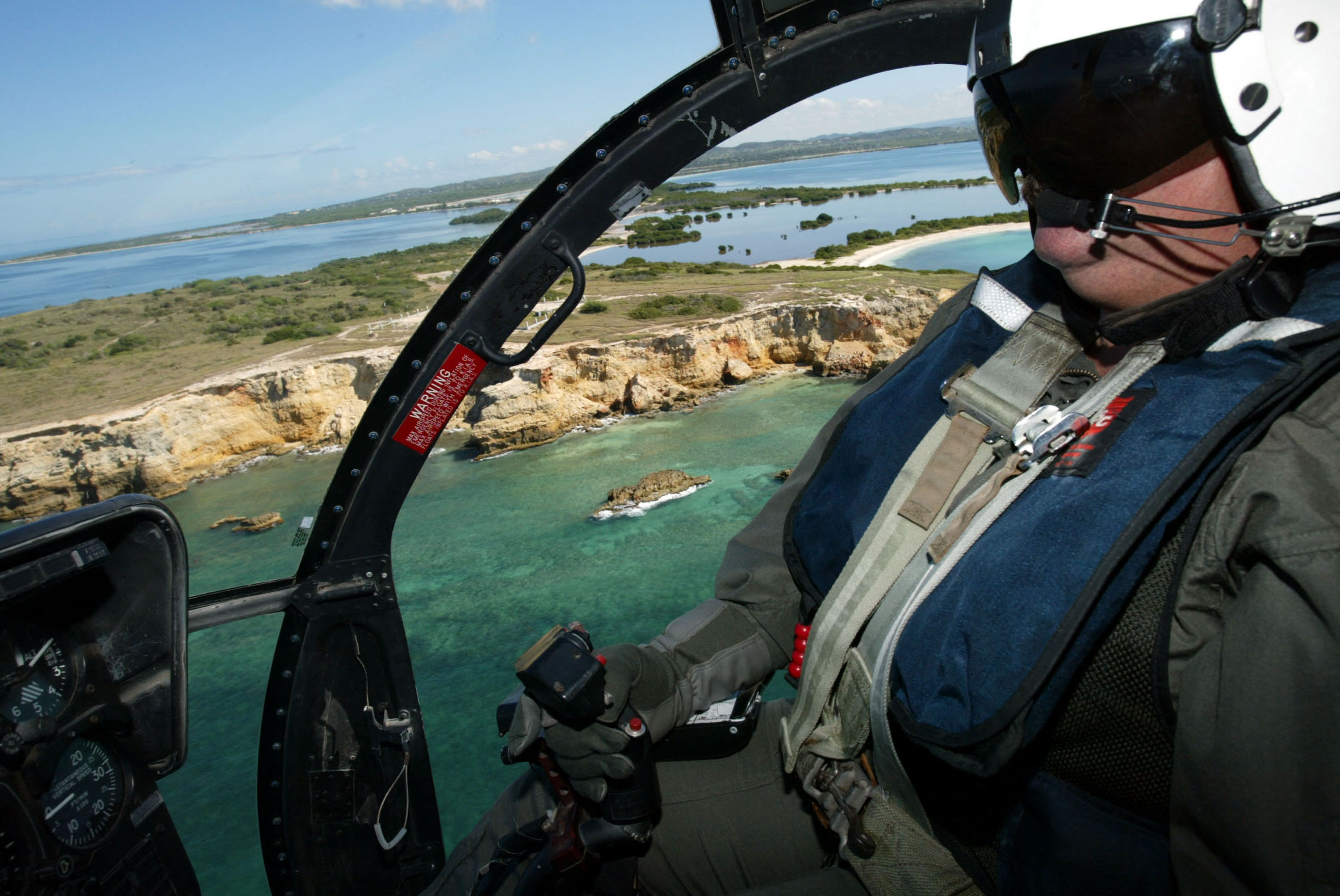 Senior U.S. Border Patrol Agent David Rodriquez flies in a helicopter looking for illegal migrants 24 April 2004 near Mayaguez, Puerto Rico. A record number of migrants from the Dominican Republic are trying to illegally enter the United States through Puerto Rico. The total number of unlawful migrants attempting to enter Puerto Rico during the 2004 fiscal year is 5,756 as apposed to a total of 3, 477 for all of the 2003 fiscal year. Due to a sagging economy, rising cost of living and high unemployment people are fleeing the Dominican Republic in search of a better life. (Joe Raedle/Getty Images/AFP) FOR NEWSPAPERS AND TV USE ONLY *** Local Caption *** (Photo by JOE RAEDLE / Getty Images North America / Getty Images via AFP)
