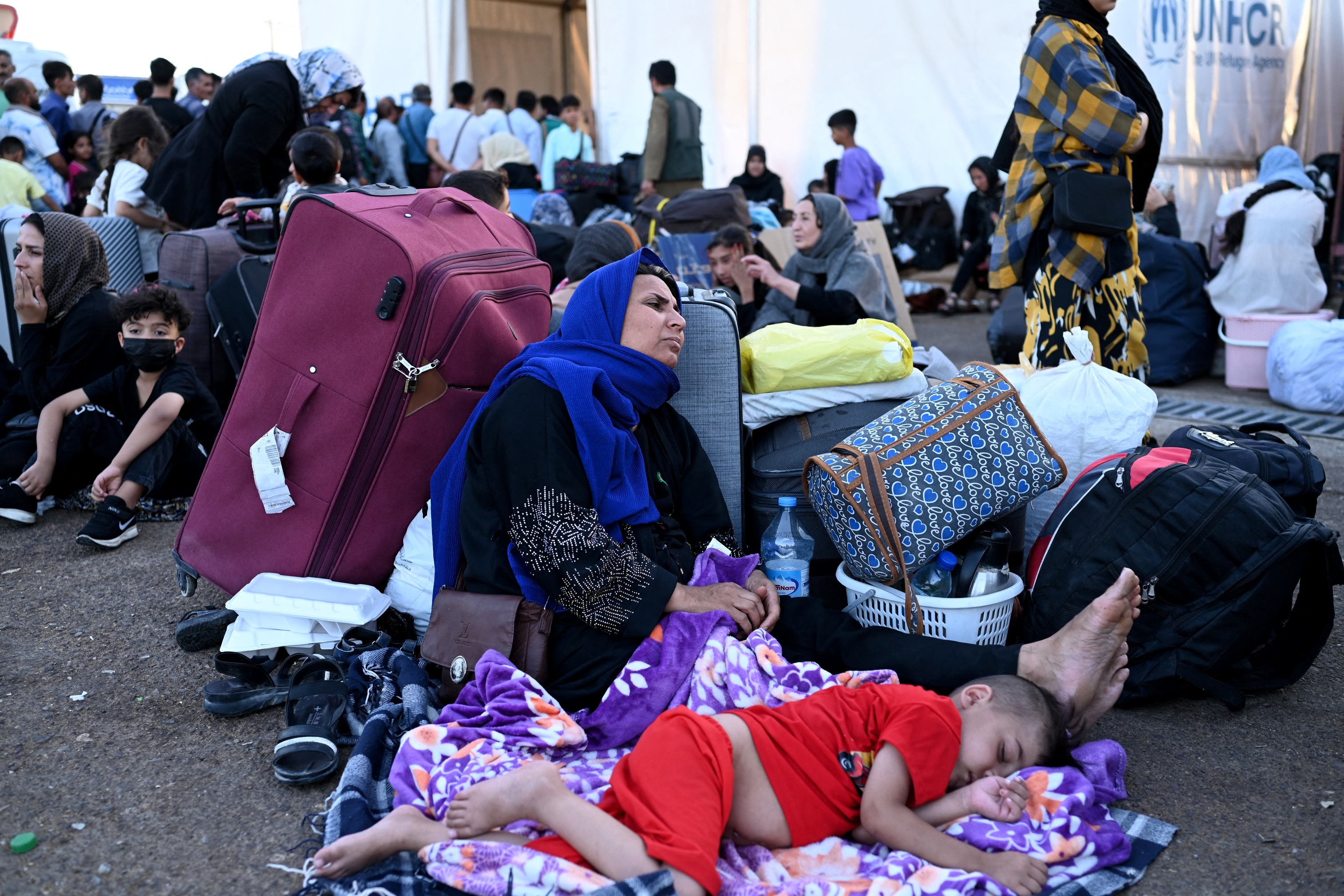 Afghan refugees rest with their belongings at a border crossing.