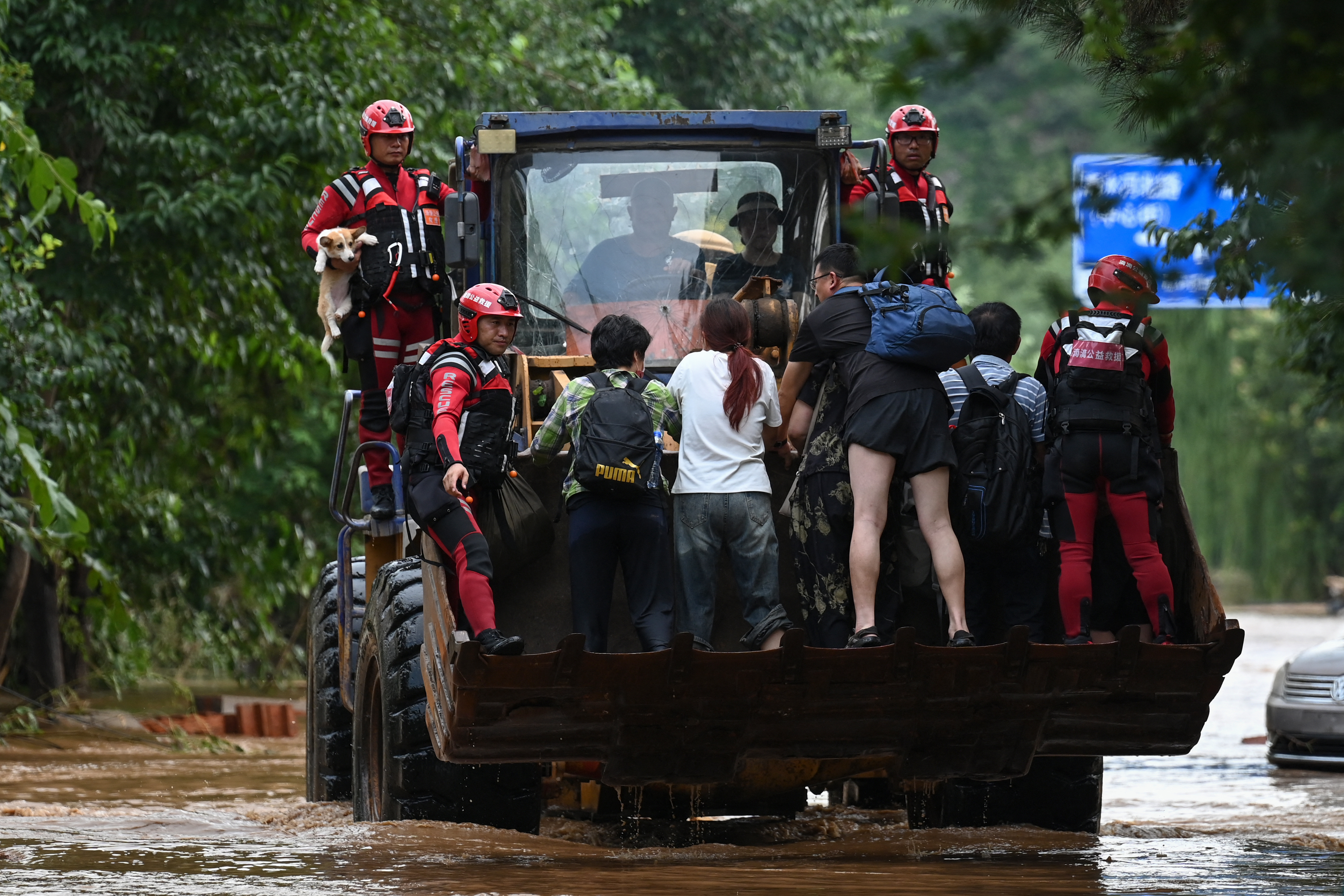 Rescue team members evacuate residents from their home on a flooded road.