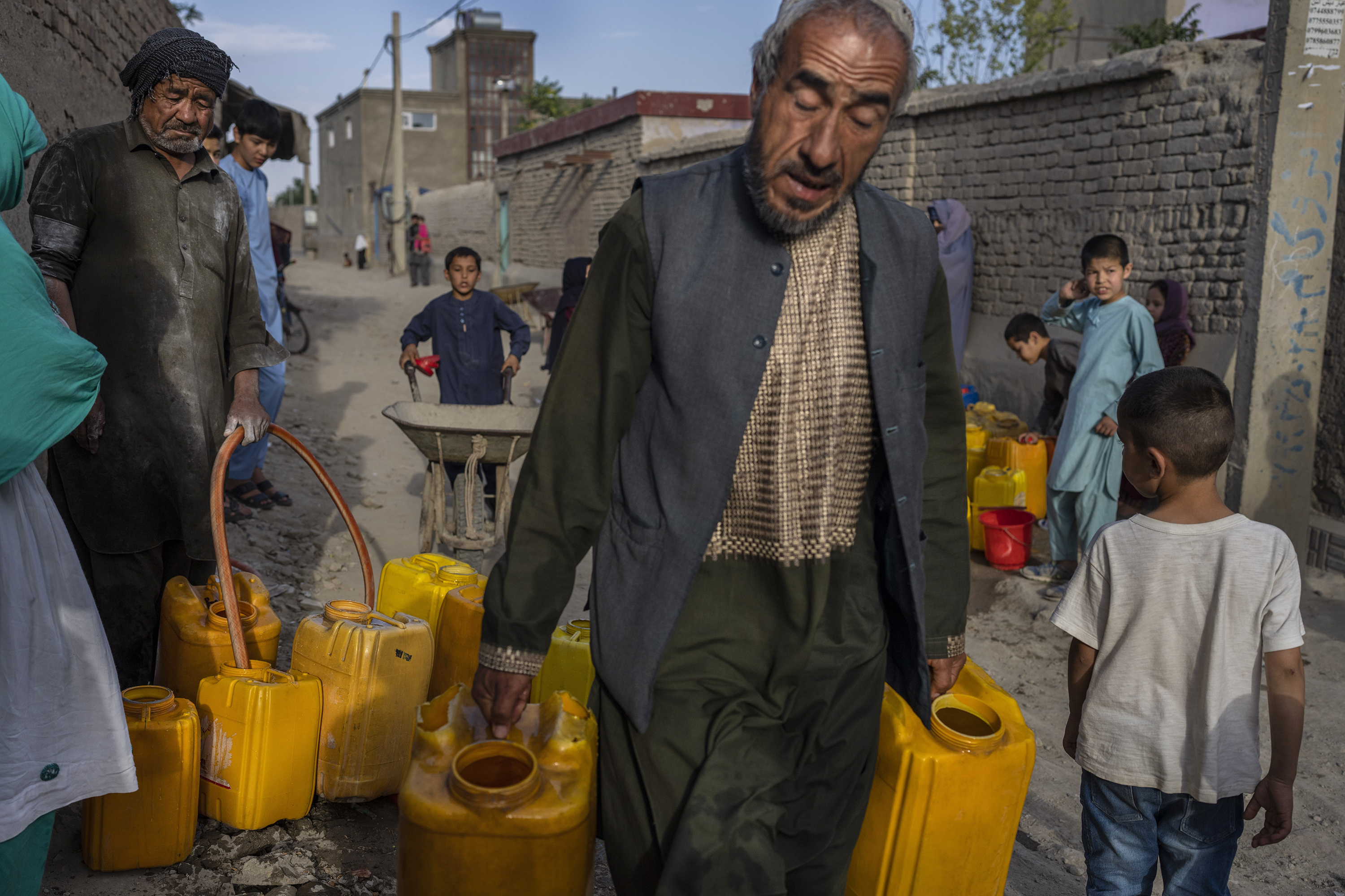 Neighbors gather to fill their drums with drinking water in Azara neighborhood in Kabul, Afghanistan, Wednesday, June 14, 2023. (AP Photo/Rodrigo Abd)