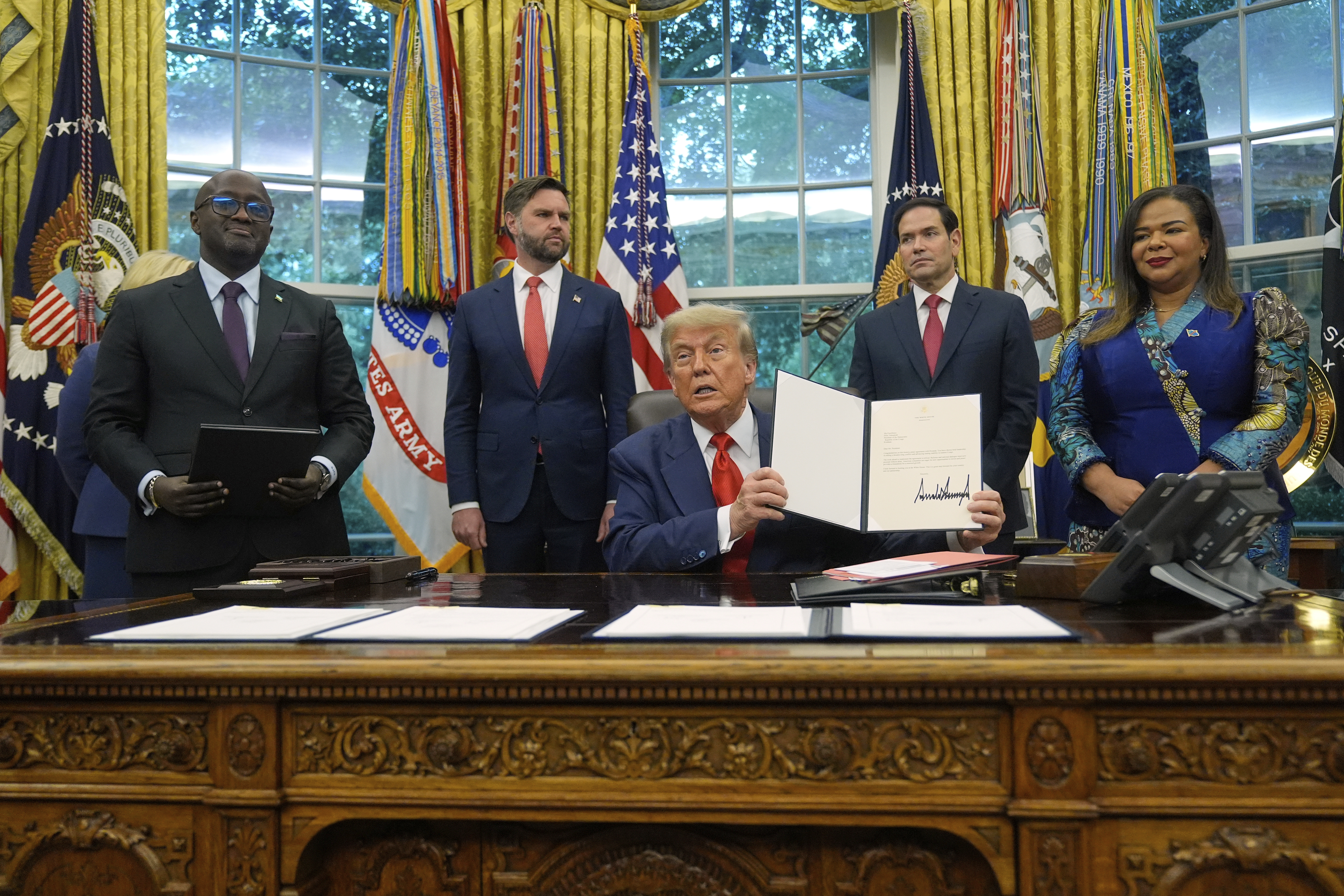 President Donald Trump holds up a signed document, with Congo's Foreign Minister Therese Kayikwamba Wagner, Rwanda's Foreign Minister Olivier Nduhungirehe, US Vice President JD Vance and Secretary of State Marco Rubio.