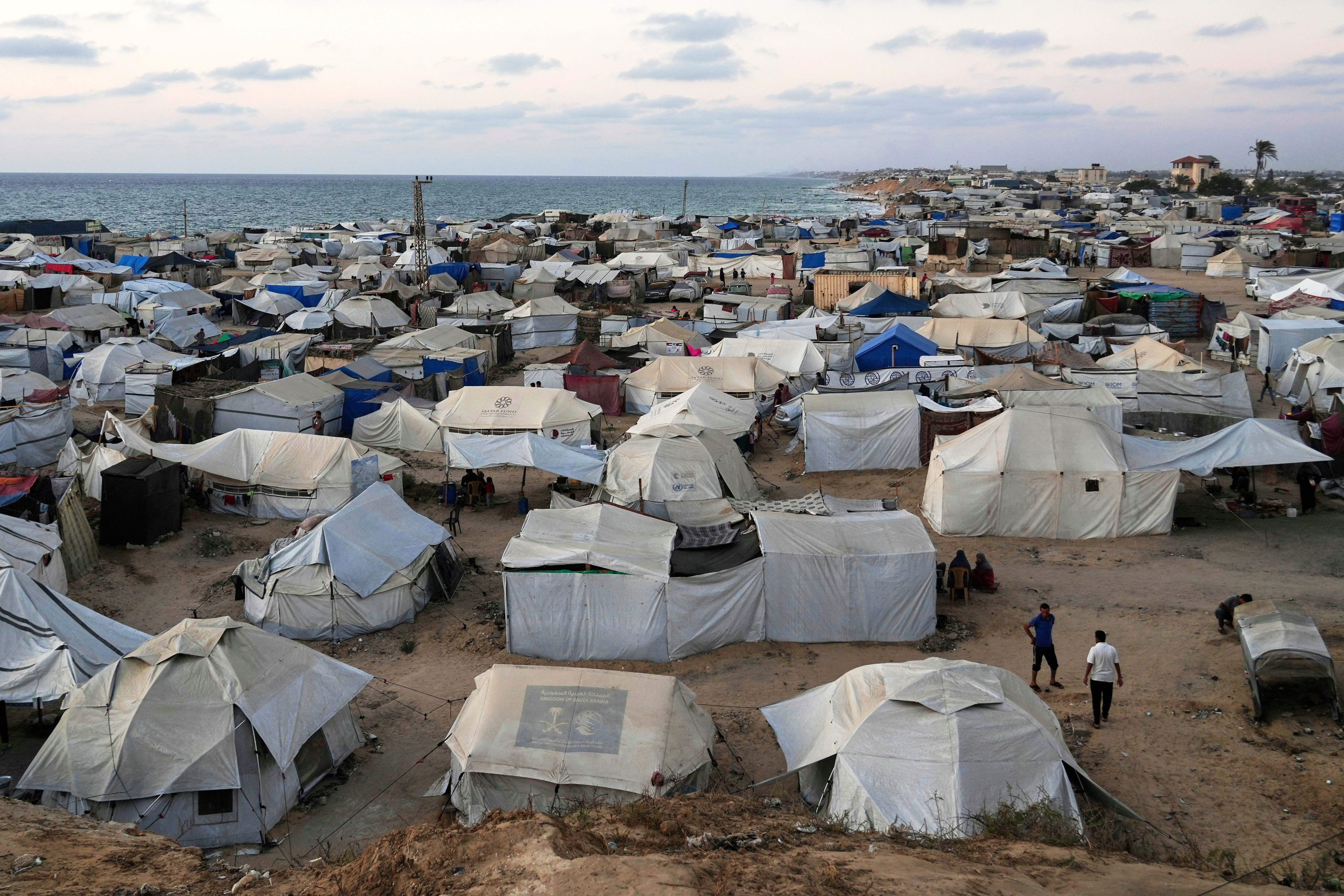 Palestinians displaced by the Israeli air and ground offensive on the Gaza Strip, stand in an area at a makeshift tent camp at dusk in Khan Younis, Gaza Strip, Wednesday, July 2, 2025. [Abdel Kareem Hana/AP]