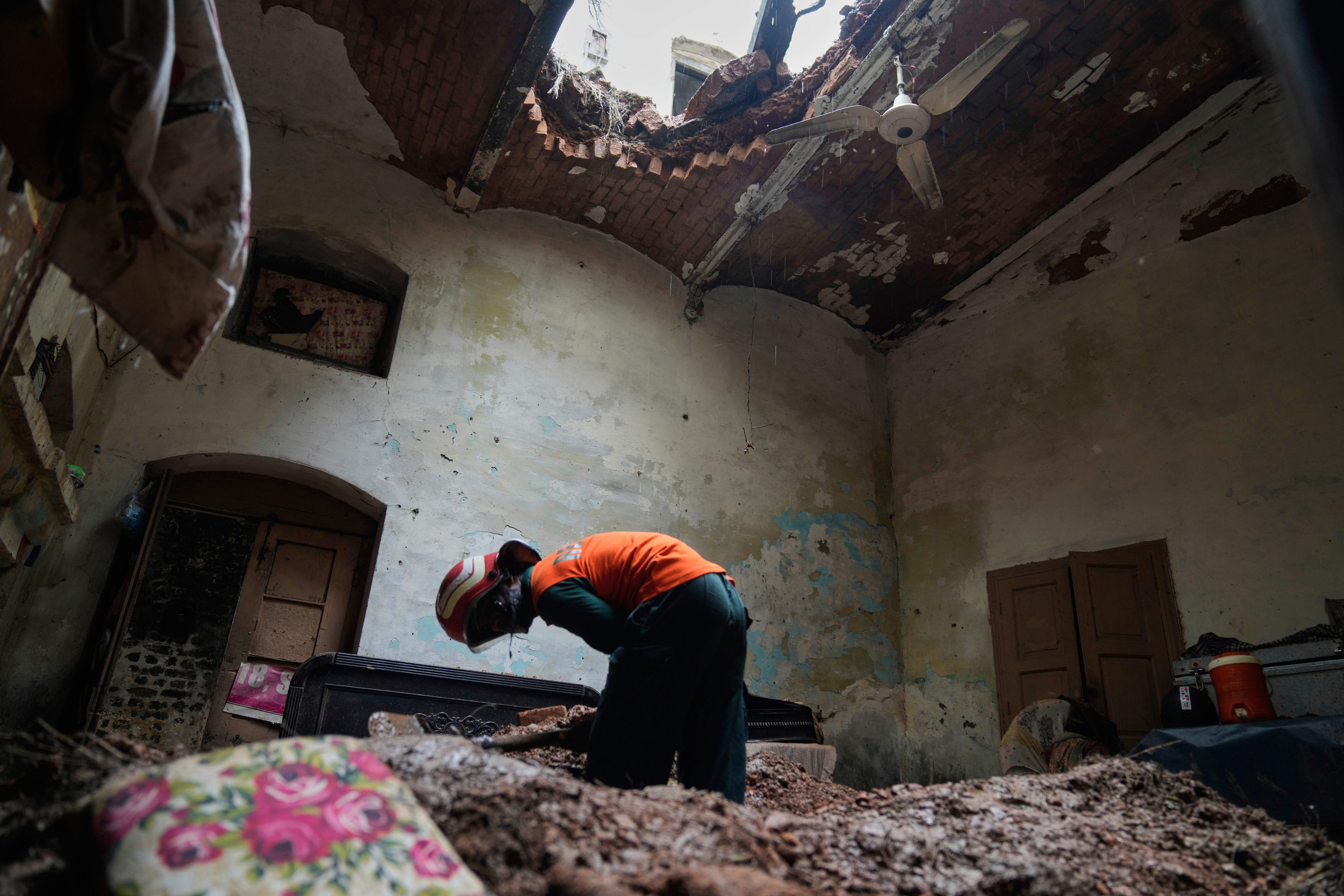A rescue worker removes debris from a house that collapsed after heavy rain in Lahore, Pakistan, Thursday, July 10, 2025. (AP Photo/K.M. Chaudary)