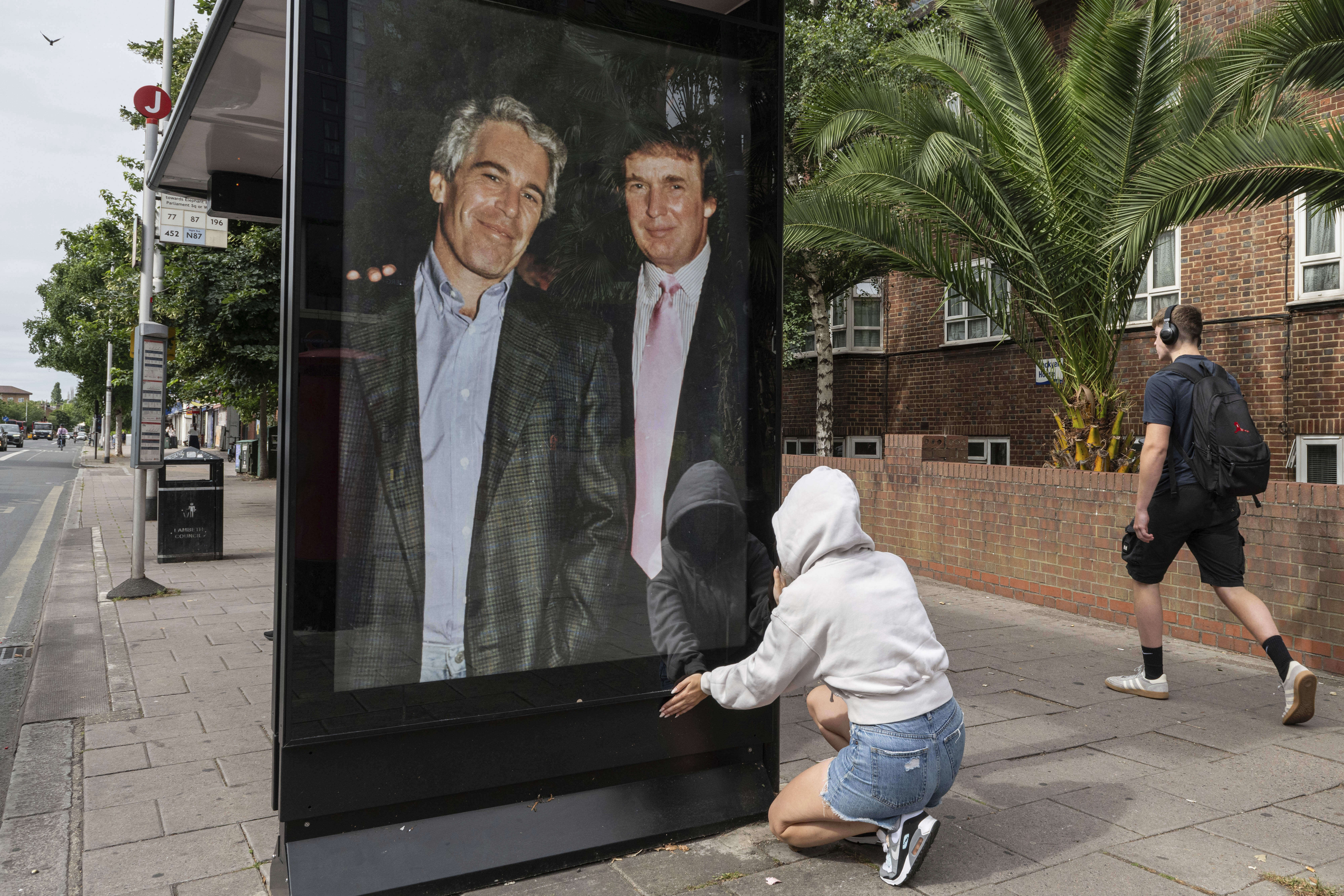 Activists put up a poster showing President Donald Trump and Jeffrey Epstein near the U.S. Embassy in London, Thursday, July 17, 2025.(AP Photo/Thomas Krych)
