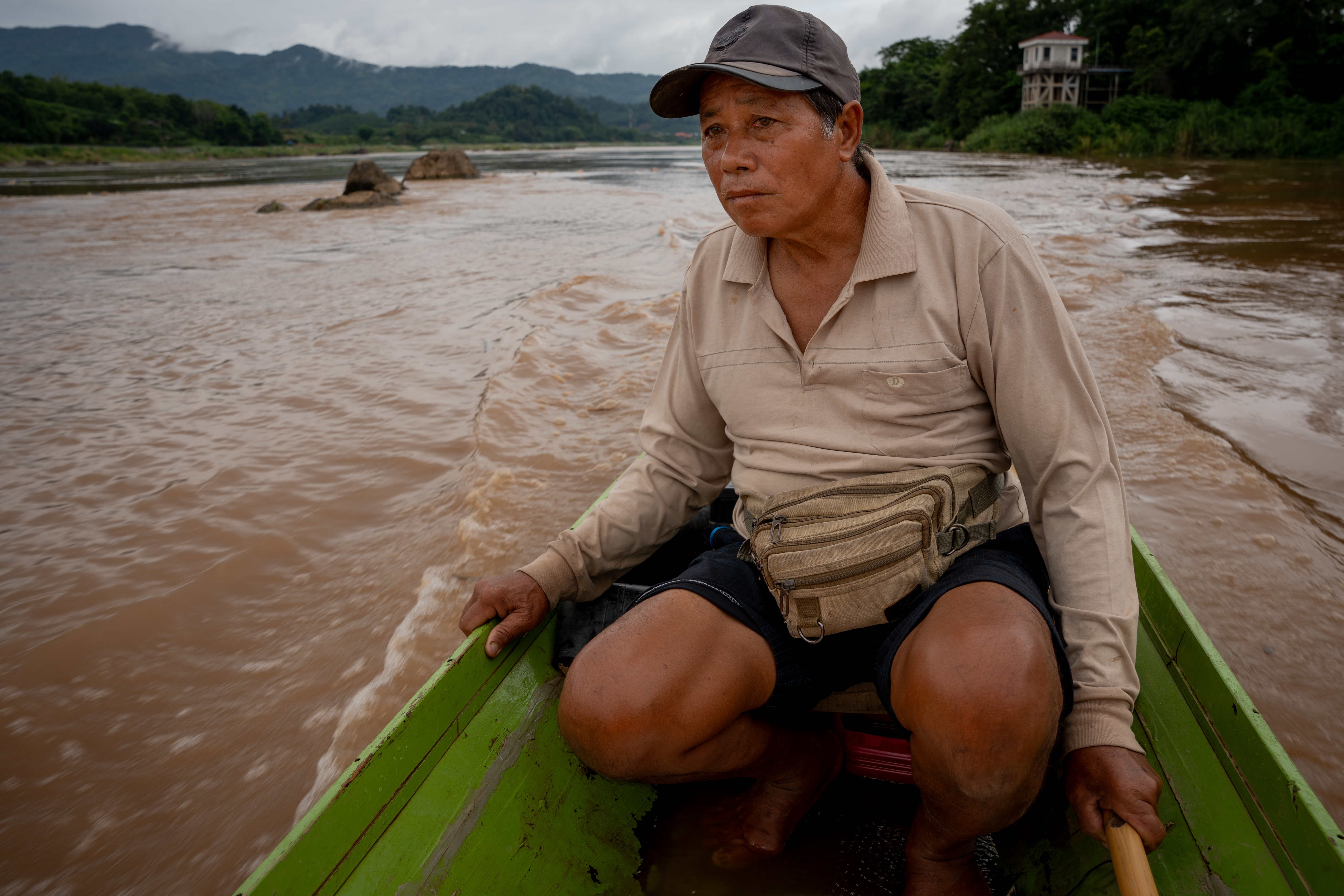 Hom Phan, 67, steering his fishing boat on the Mekong River [Fabio Polese/Al Jazeera]