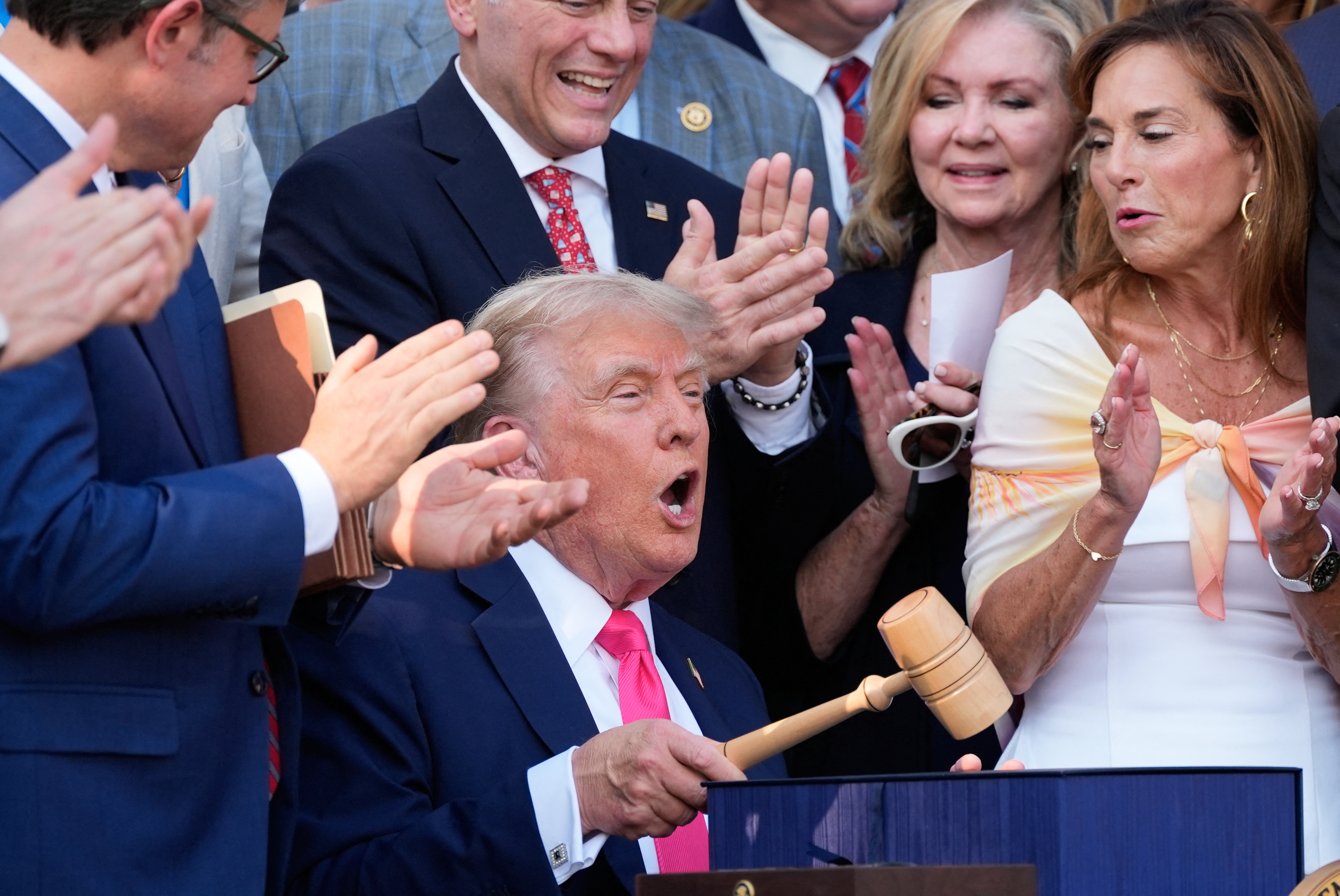US President Donald Trump bangs a gavel after signing his signature bill of tax breaks and spending cuts "Big Beautiful Bill" on the South Lawn of the White House in Washington, DC on July 4, 2025. (Photo by Alex Brandon / POOL / AFP)