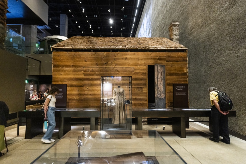 a small wooden cabin is seen inside a museum
