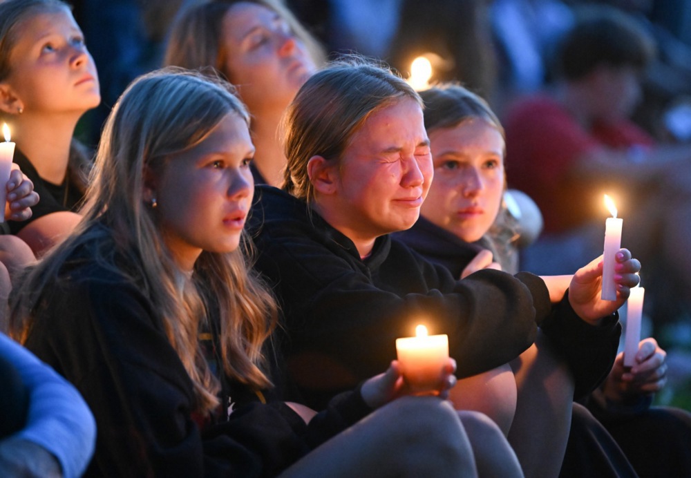 epa12328602 A child becomes emotional as they listen to speakers during a candle light vigil at a local park for the shooting at the Annunciation Catholic School in Minneapolis, Minnesota, USA, 27 August 2025. Two children were killed and 17 others wounded before the gunman took his own life. EPA/CRAIG LASSIG