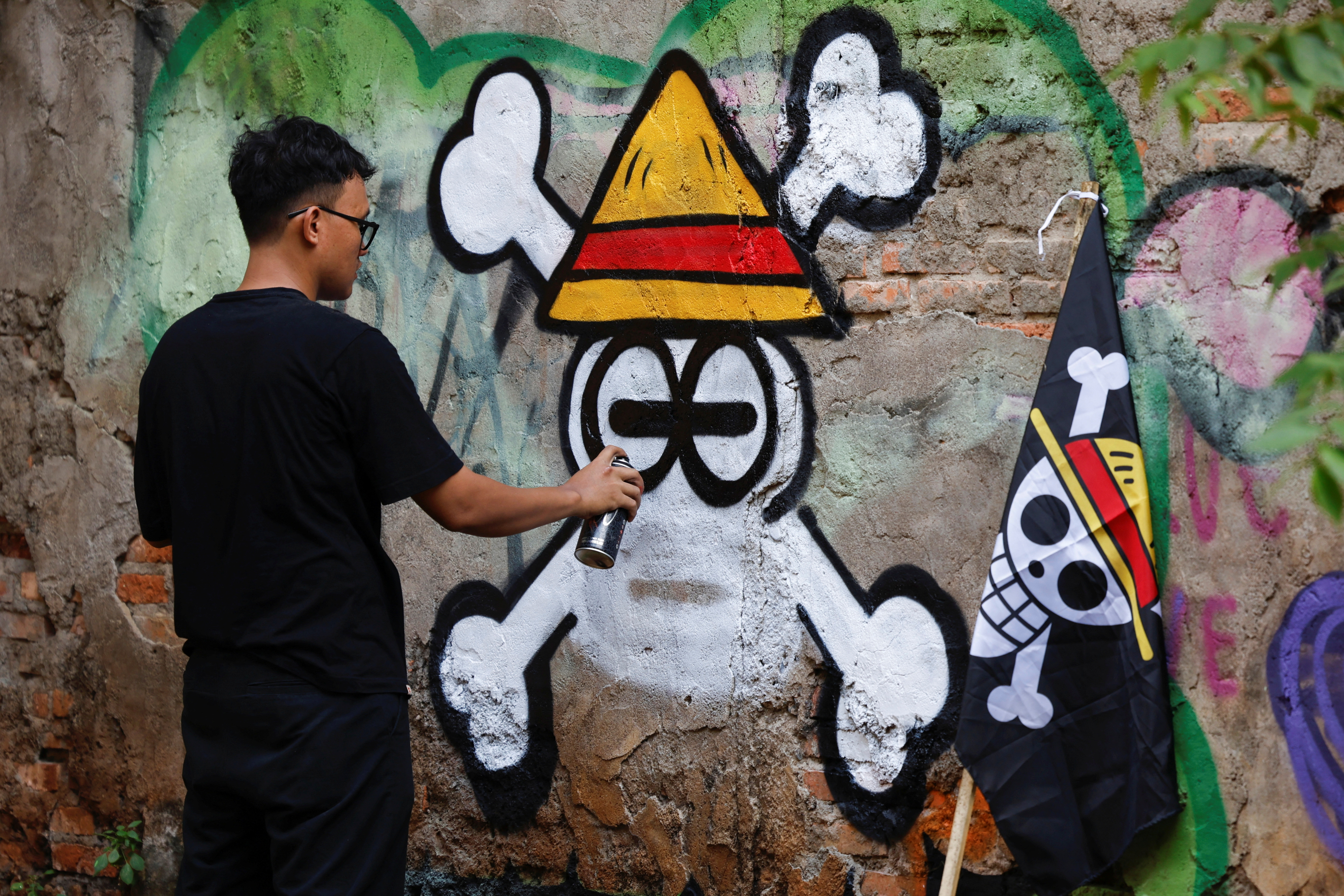 Kemas Muhammad Firdaus, 28, paints a mural depicting a Jolly Roger from the popular Japanese anime and manga series 'One Piece' in Bekasi, West Java province, Indonesia, August 7, 2025. REUTERS/Ajeng Dinar Ulfiana