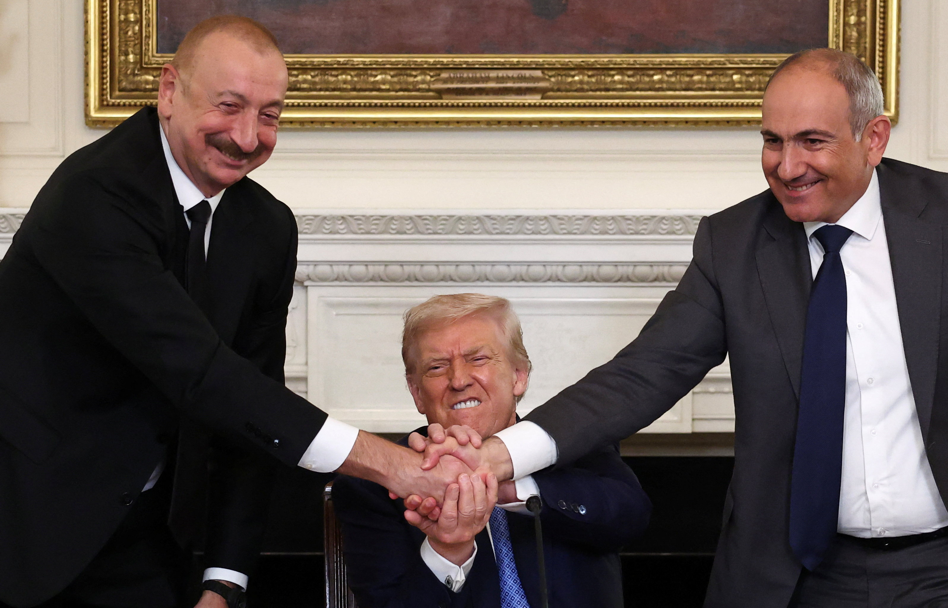 US President Donald Trump holds the hands of Azerbaijan's President Ilham Aliyev and Armenia's Prime Minister Nikol Pashinyan as they shake hands.