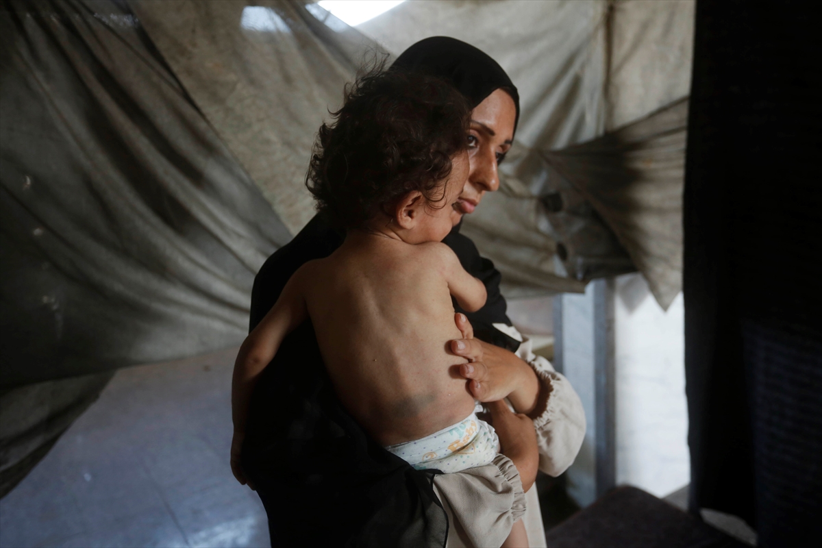 a mother holds a small child in her arms in a tent