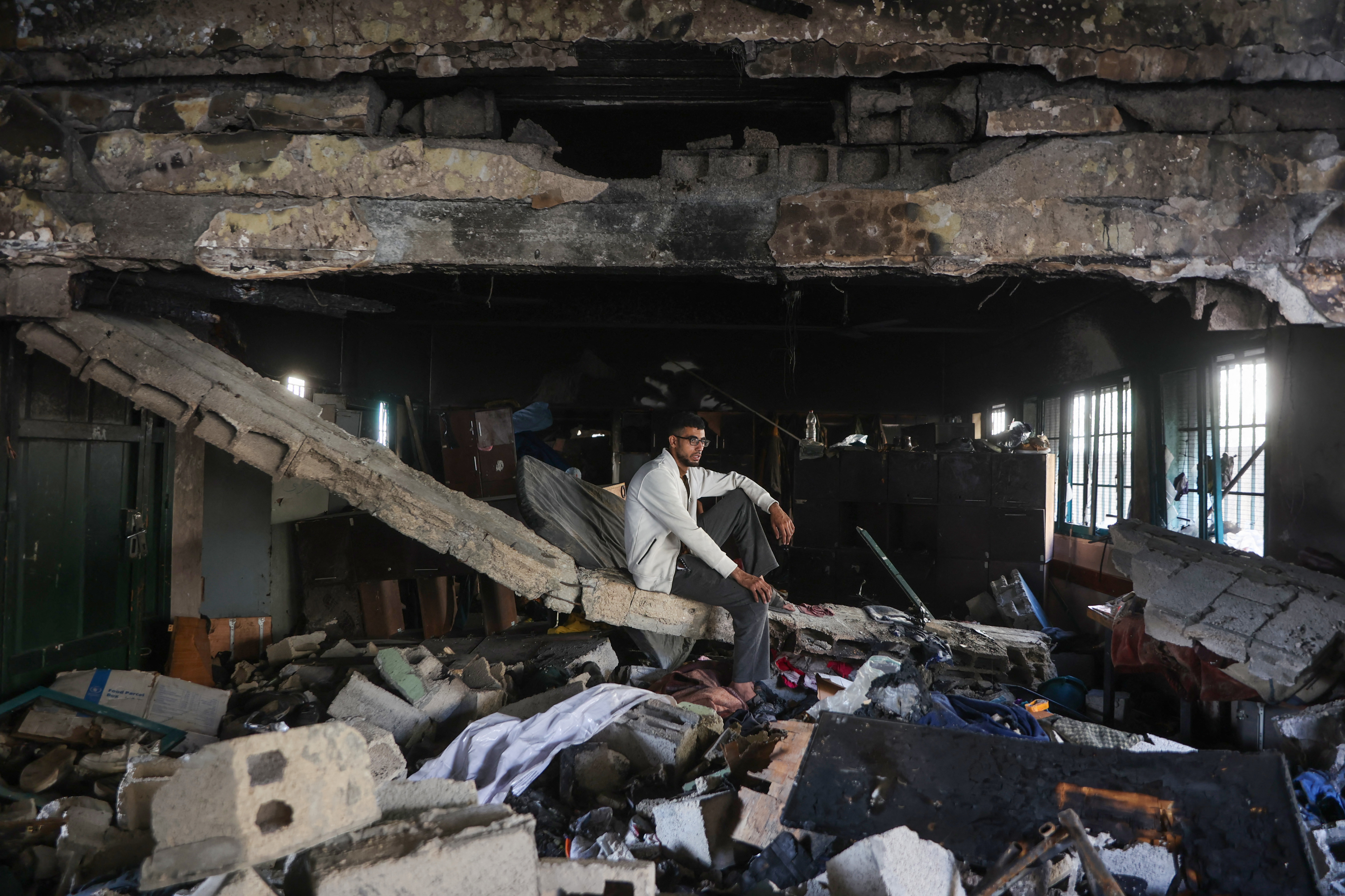 A man sits amid the debris at the Fahmi Al-Jarjawi School in Gaza City on May 26, 2025, following an Israeli strike. Rescuers said devastating Israeli strikes in the Gaza Strip killed at least 52 people on May 26, 33 of them in a school turned shelter. (Photo by Omar AL-QATTAA / AFP)