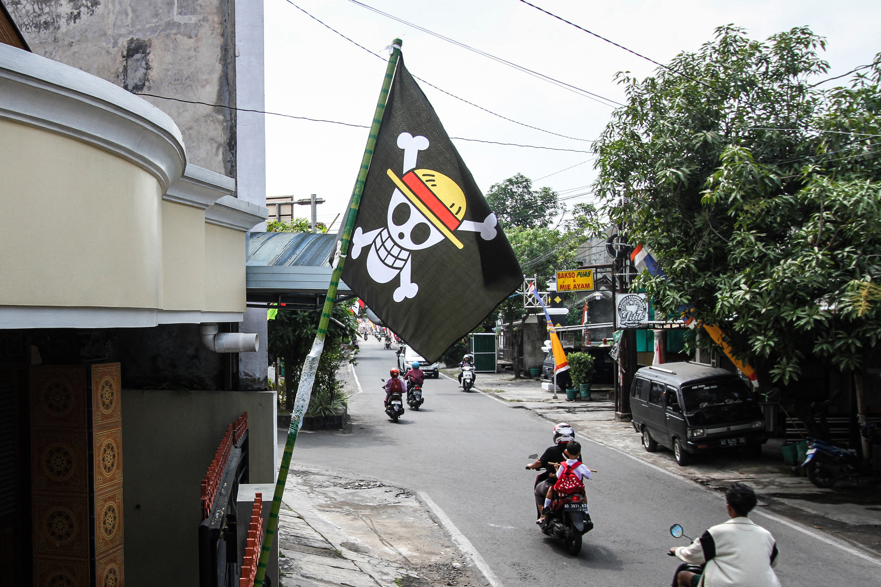 A pirate flag from the Japanese anime One Piece, installed a week earlier to follow an internet trend using the symbol to criticise government policies, is seen at a house in Solo, Central Java, on August 7, 2025, ahead of the country ' s 80th Independence Day. As Indonesia's independence day approaches red and white flags will be flown across the country, but a viral anime pirate banner has drawn government threats against flying the swashbuckling ensign. A Jolly Roger skull and bone symbol topped with a straw hat from Japan's anime series 'One Piece' has caused concern among officials in Jakarta that it is being used to criticise President Prabowo Subianto's policies. (Photo by DIKA / AFP) / TO GO WITH 'INDONESIA-POLITICS-PROTEST-ANIME, FOCUS' BY DESSY SAGITA & JACK MOORE