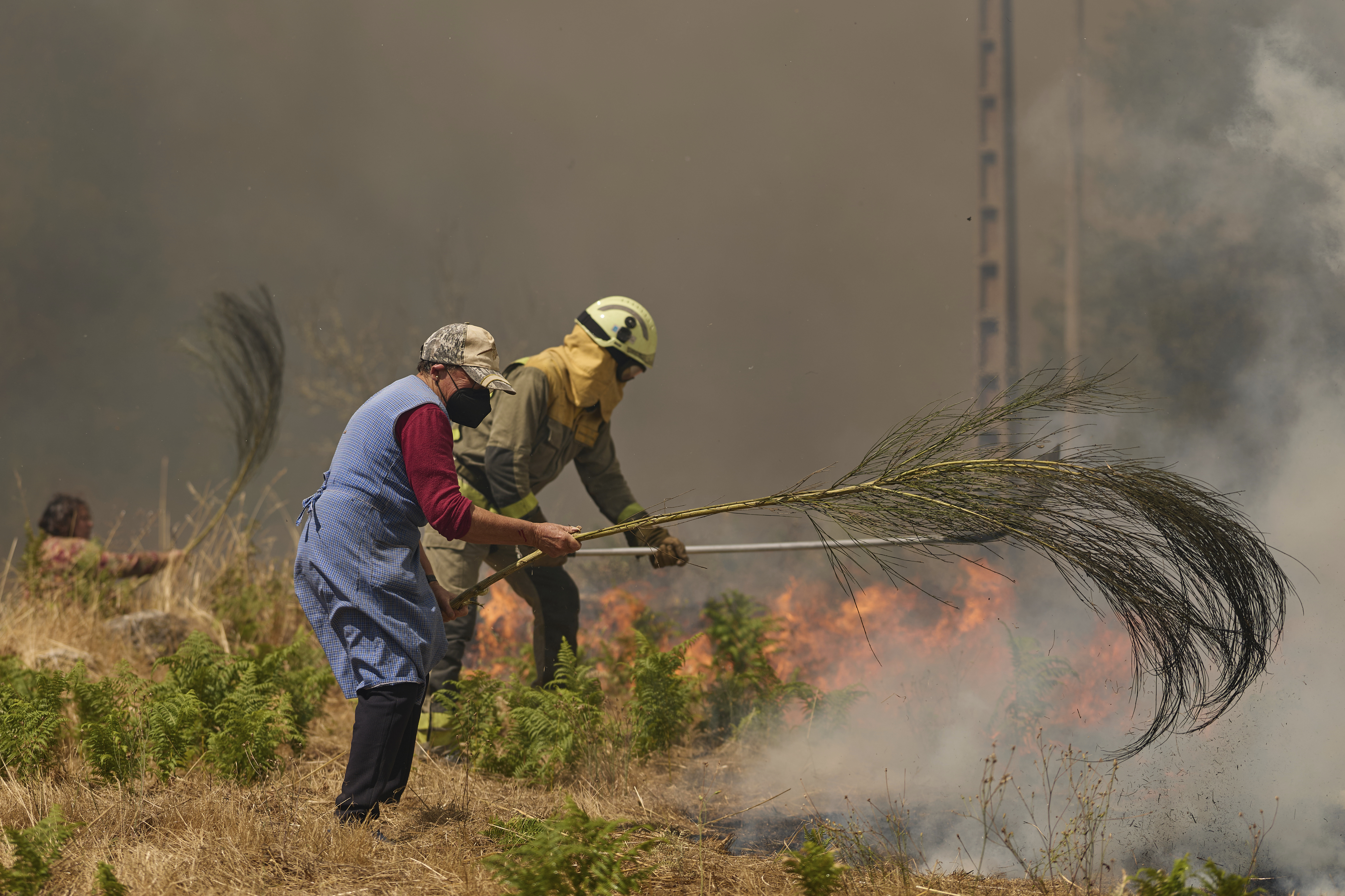 Residents and firefighters battle a fire advancing toward Rebordondo village, near Ourense, in northwestern Spain on August 18, 2025.