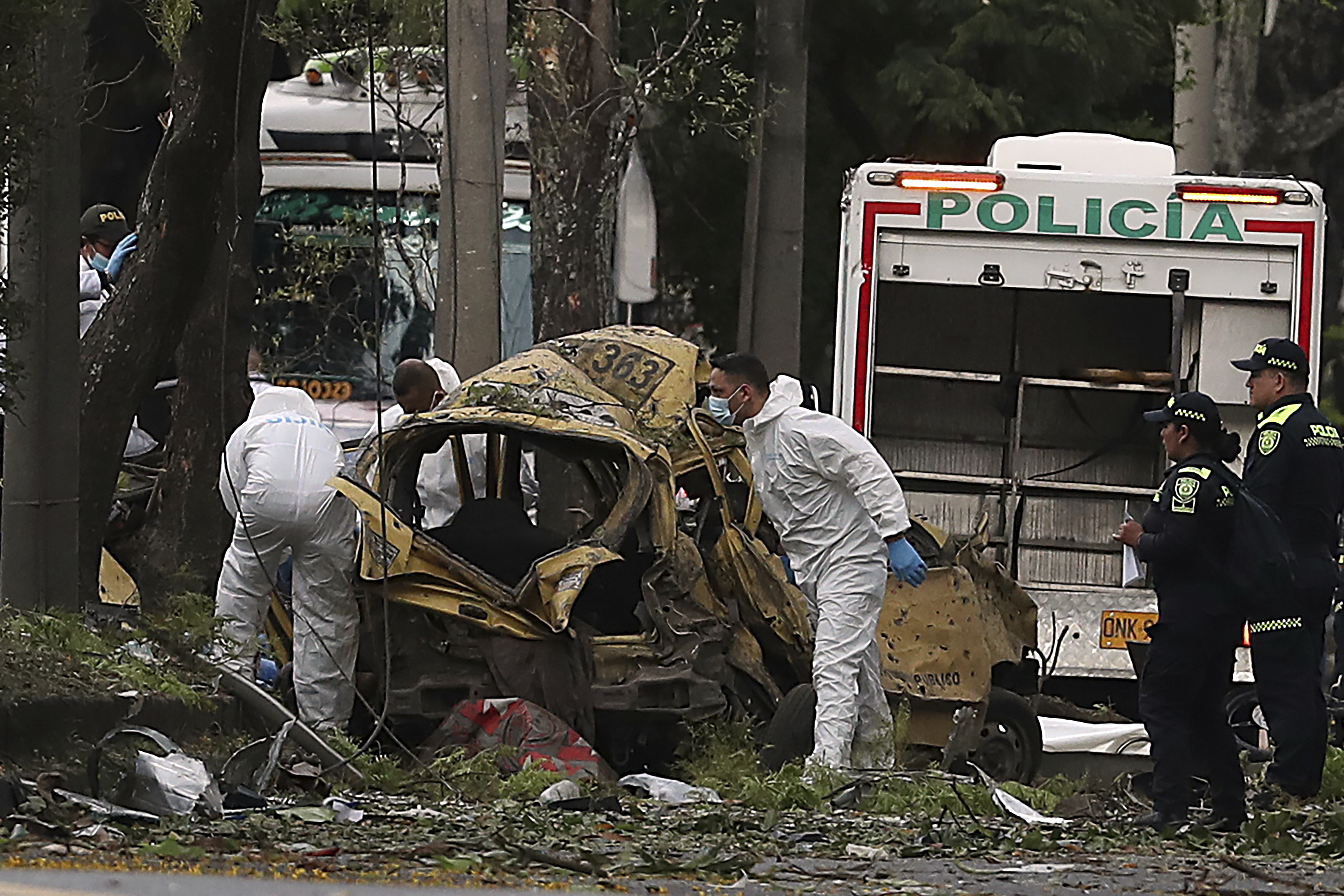 Forensics inspect the site of a bomb explosion outside an Air Force base in Cali, Colombia, Thursday, Aug. 21, 2025. (AP Photo/Santiago Saldarriaga)