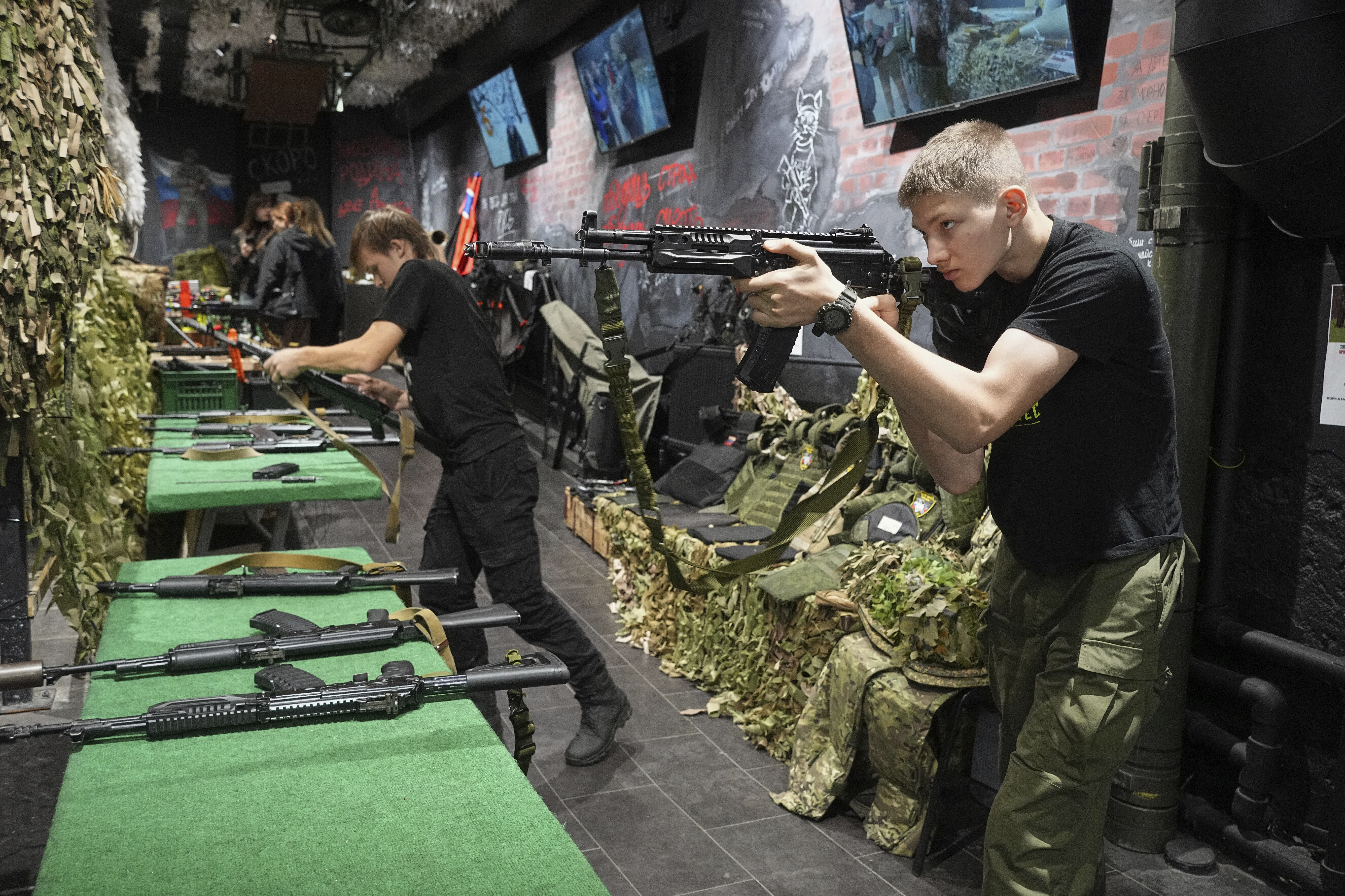 Young men practice with training Kalashnikov assault rifles at a museum of Russian Special Military Operations in Ukraine in St. Petersburg, Russia, Tuesday, Aug. 26, 2025. (AP Photo/Dmitri Lovetsky)