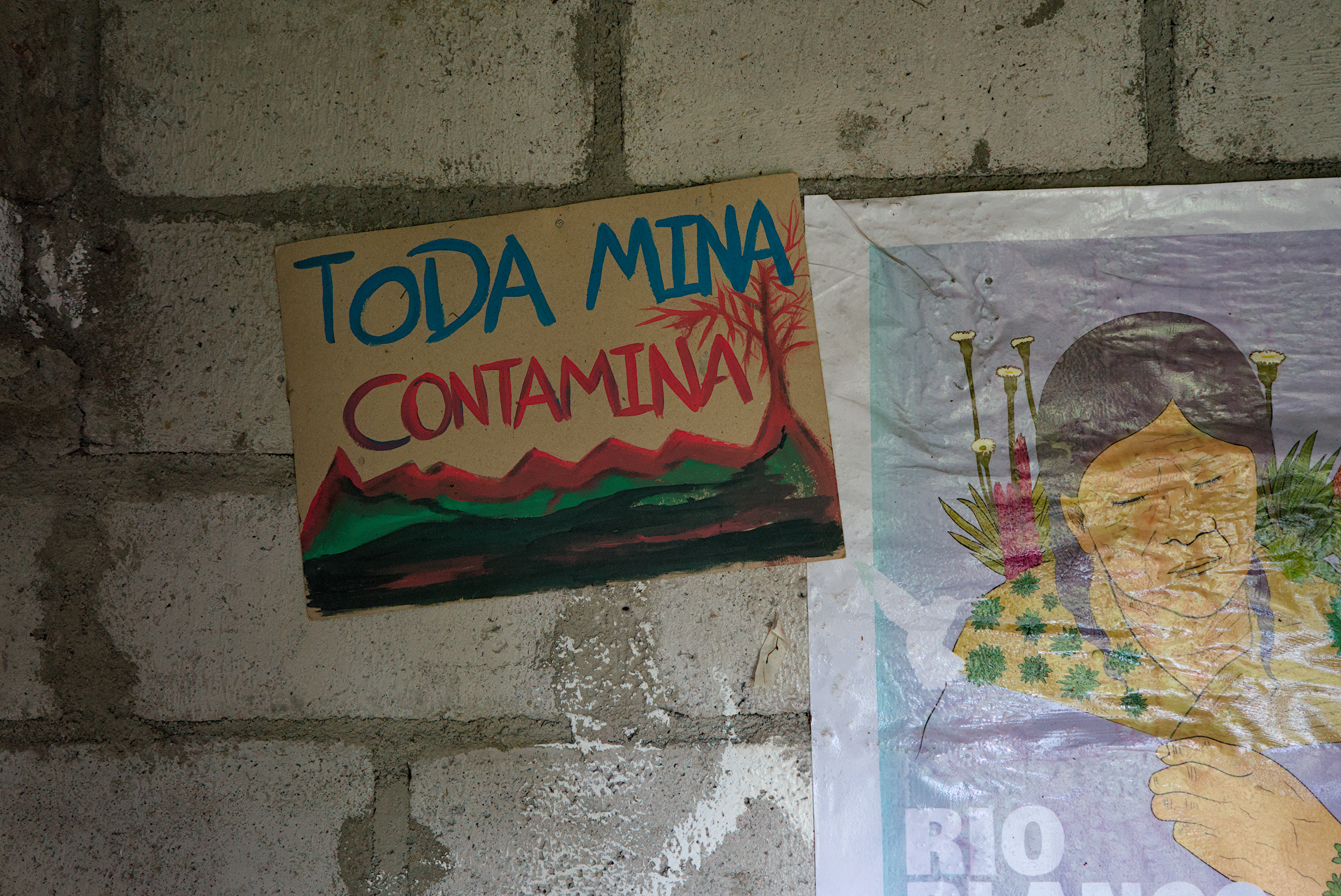 Signs on a brick wall that read, "Toda Minera Contamina."