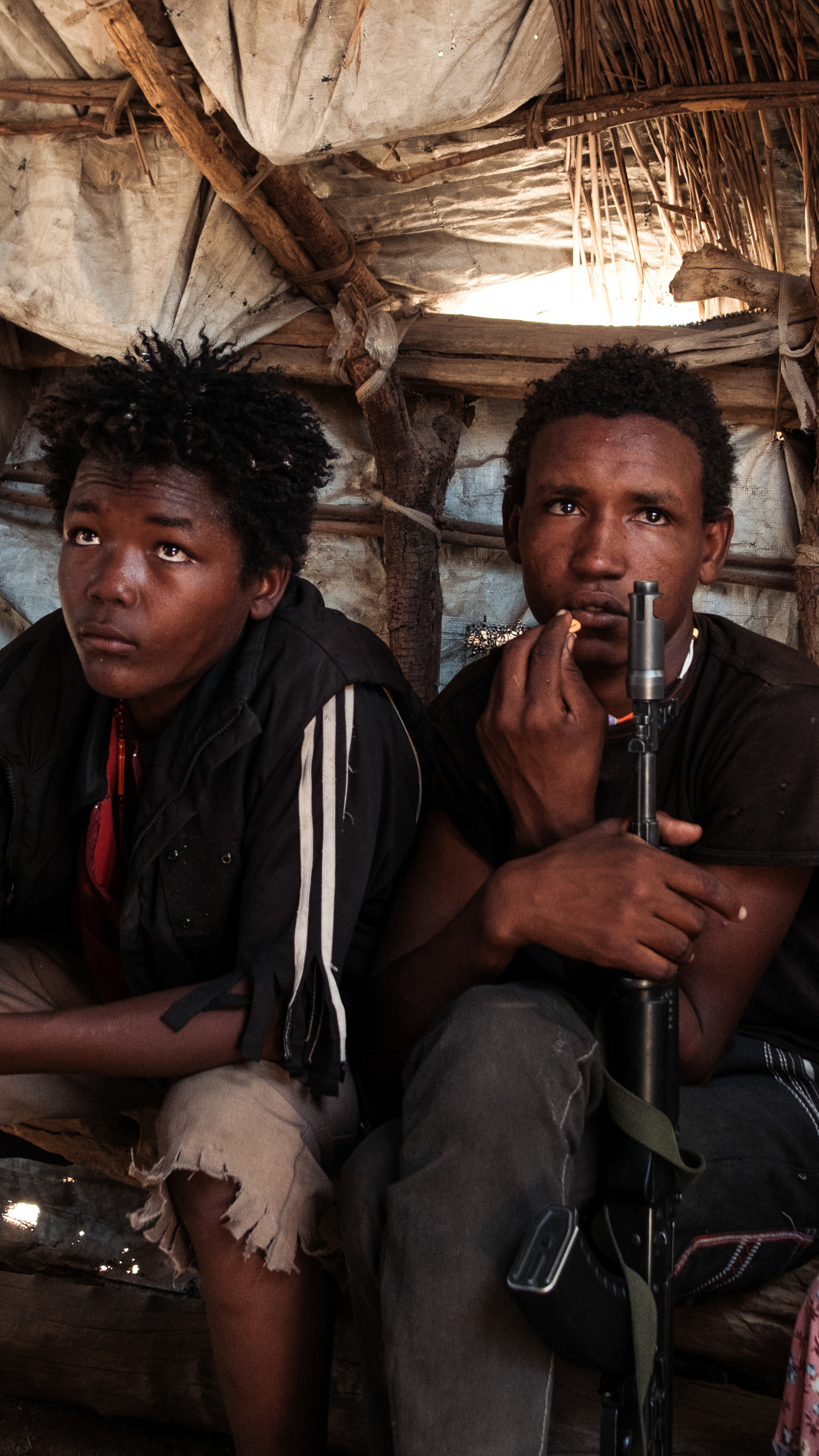 Two teenage members of the RSF sit in a cafe in Tongoli on April 22, 2025 [Guy Peterson/Al Jazeera]