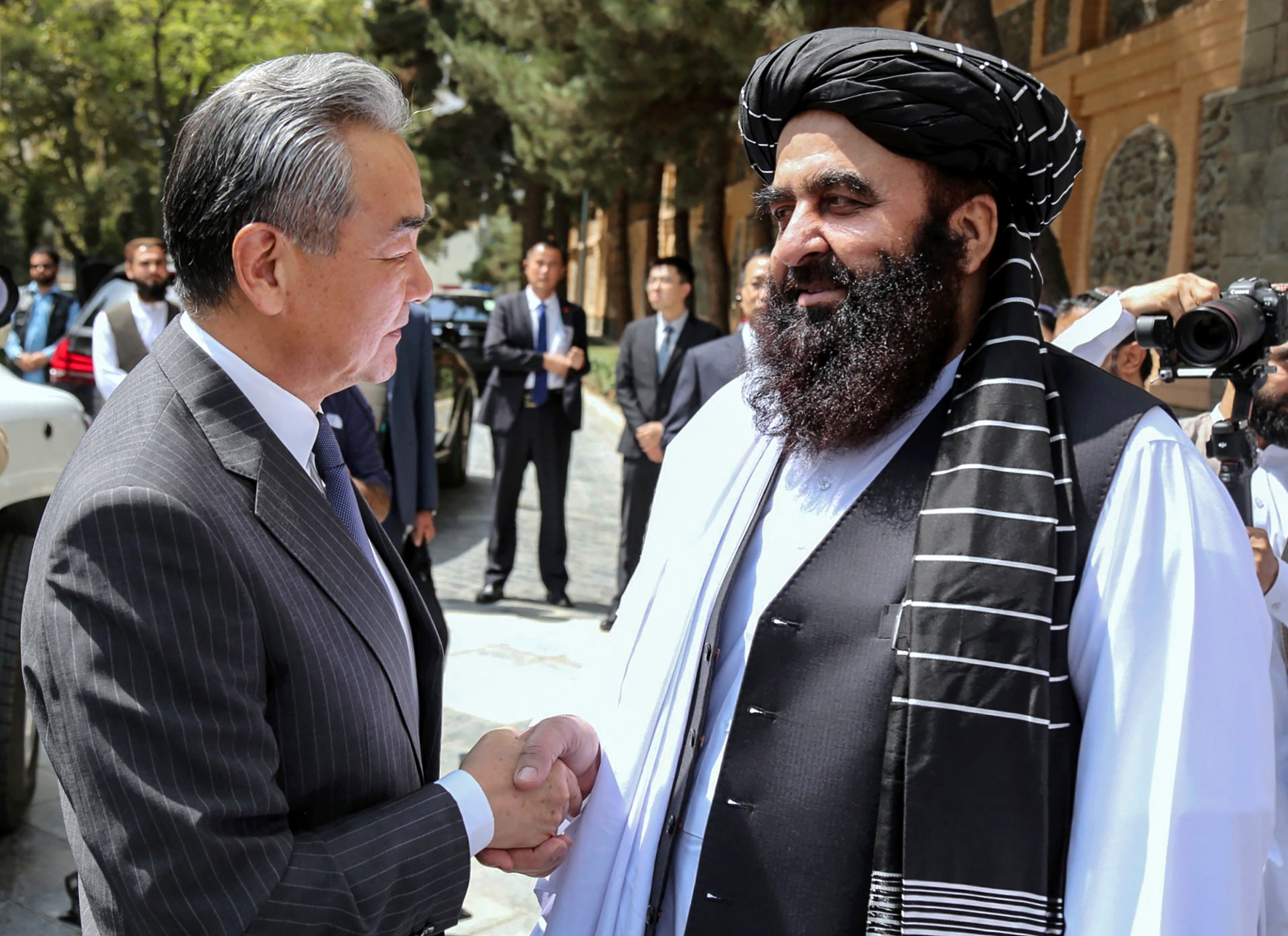 This handout photograph taken on August 20, 2025 and released by Afghanistan's Ministry of Foreign Affairs shows Afghanistan's Foreign Minister Amir Khan Muttaqi (R) welcoming China's Foreign Minister Wang Yi before their meeting in Kabul.