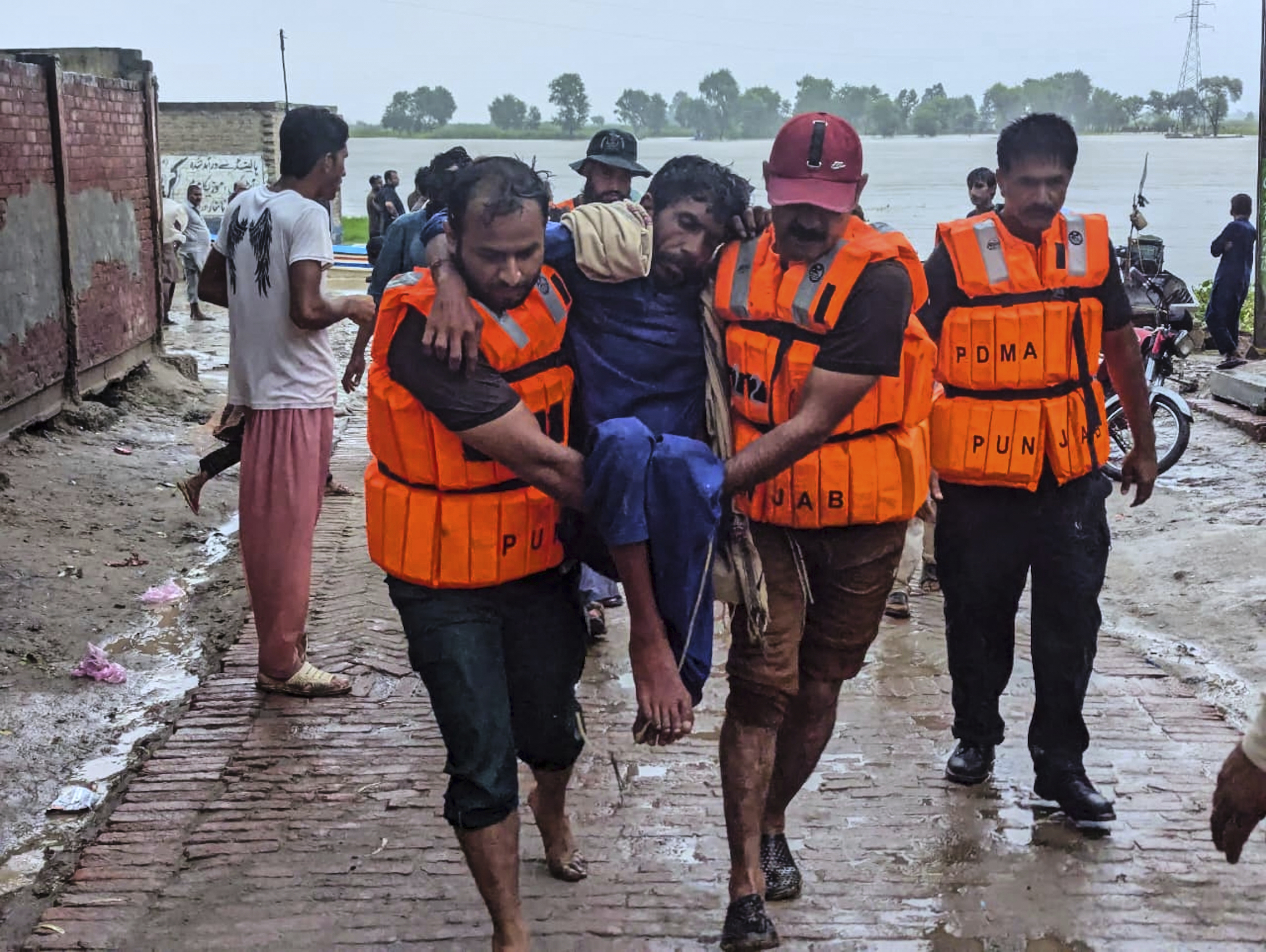 In this photo released by Pakistan's National Disaster Management Authority, rescue workers help a villager after evacuating him with others from a low-lying area due to rising water level in the Sutlej River following neighbouring India released water from overflowing dams, in Bahawalnagar a district in Pakistan's Punjab province bordering India, Tuesday, Aug. 26, 2025. (Pakistan's National Disaster Management Authority via AP)