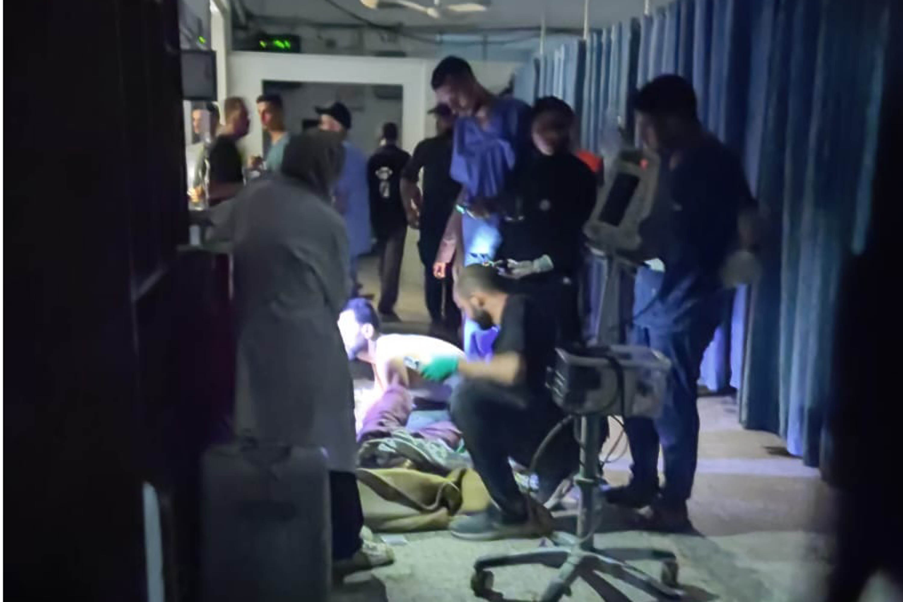 Medical staff at Al Shifa hospital treating a patient under the light of a mobile phone