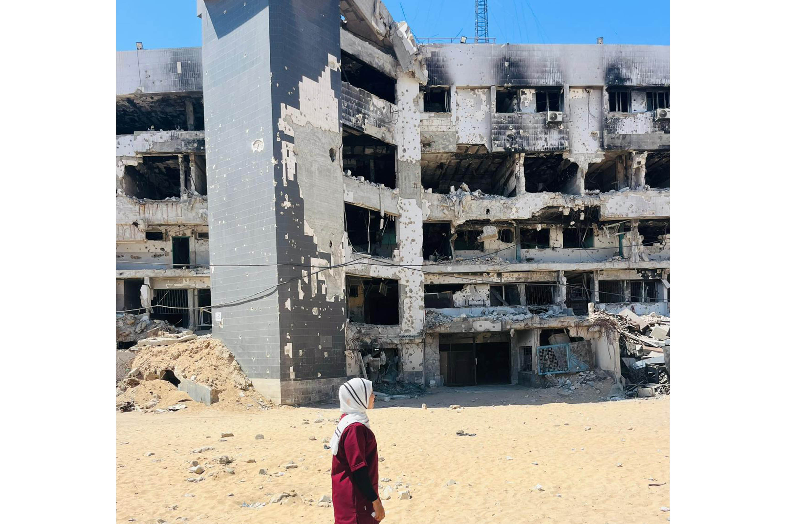 A photo of a woman in red scrubs in front of a burned out building