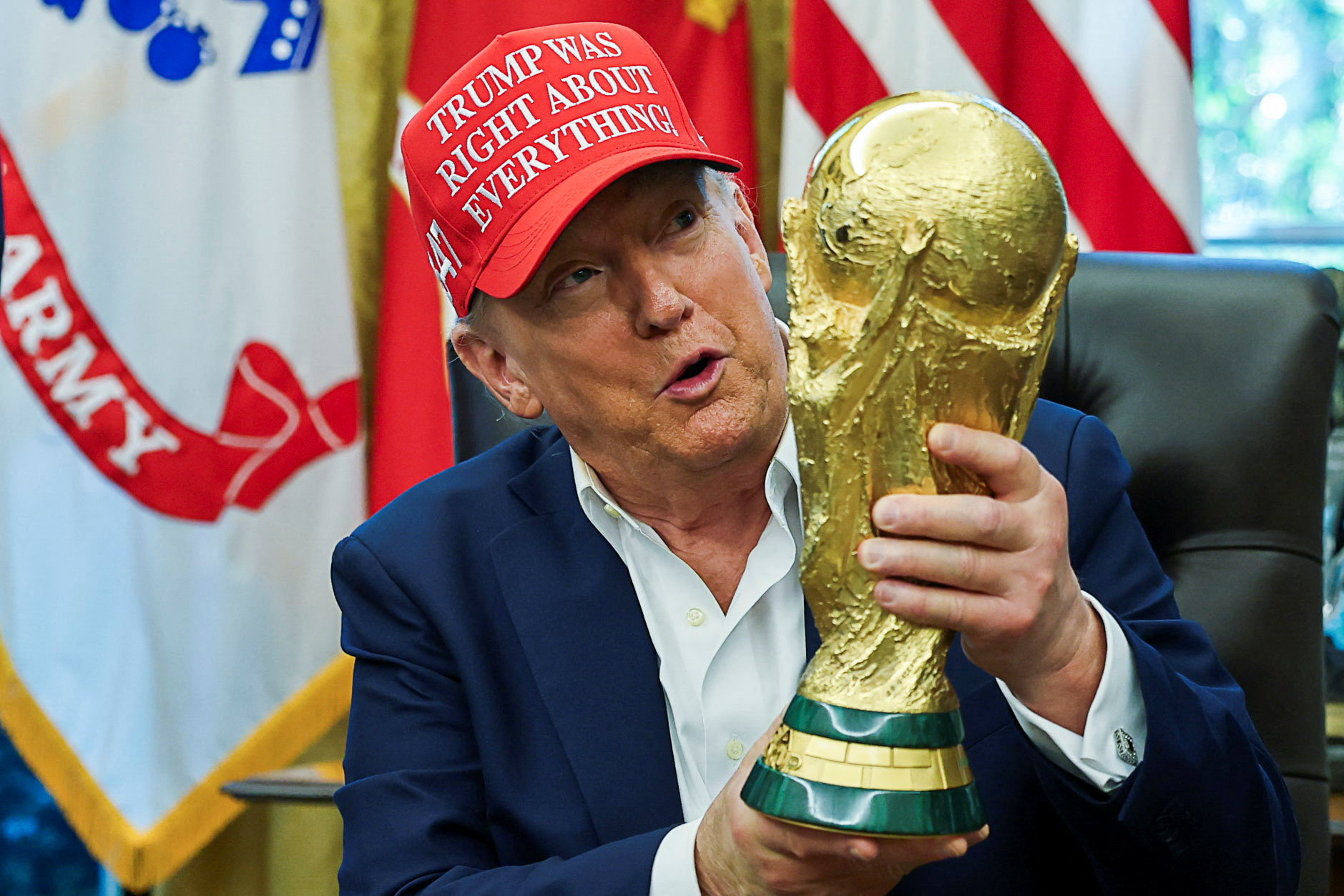 U.S. President Donald Trump wears a 'Trump Was Right About Everything!' hat while holding the FIFA World Cup Trophy, as he makes an announcement on the 2026 FIFA World Cup, in the Oval Office at the White House in Washington, D.C.