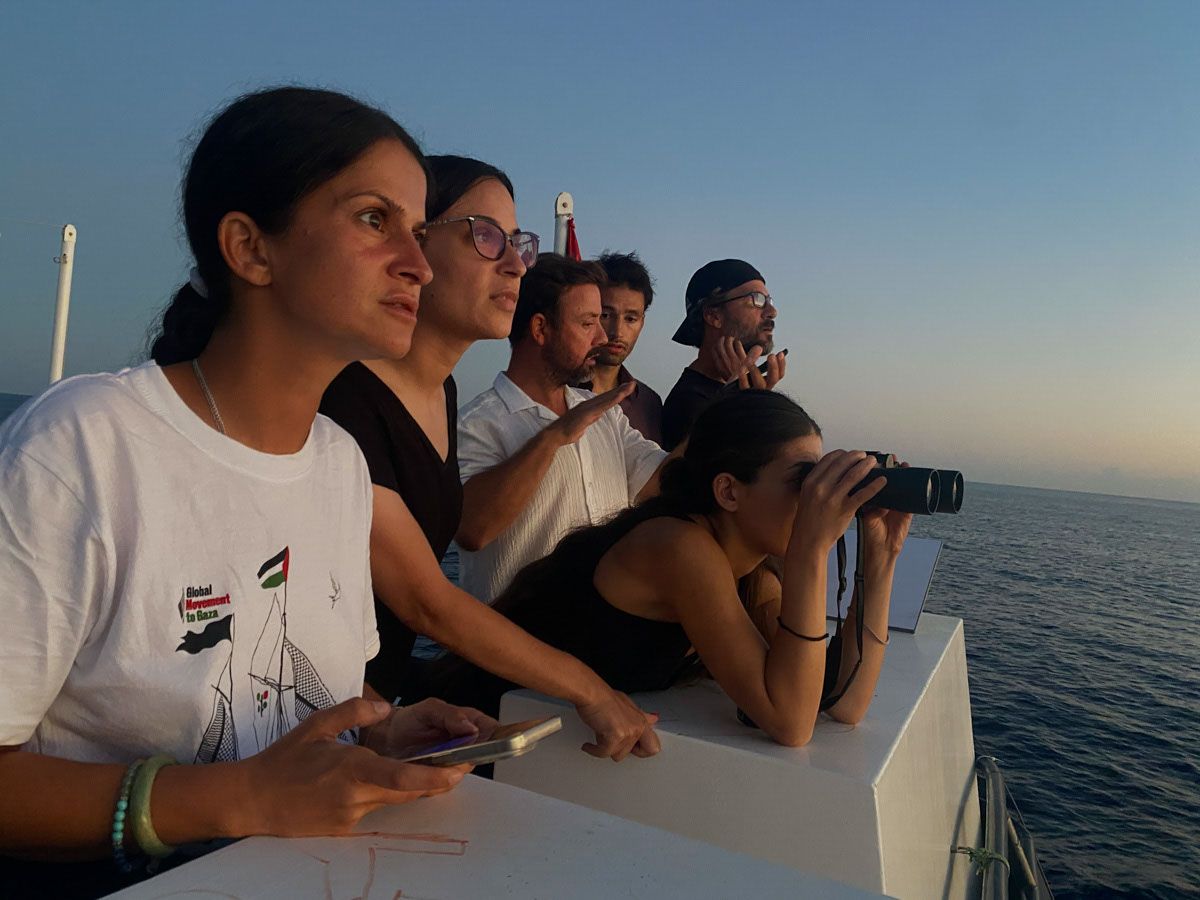 Activists look out across the water from a ship